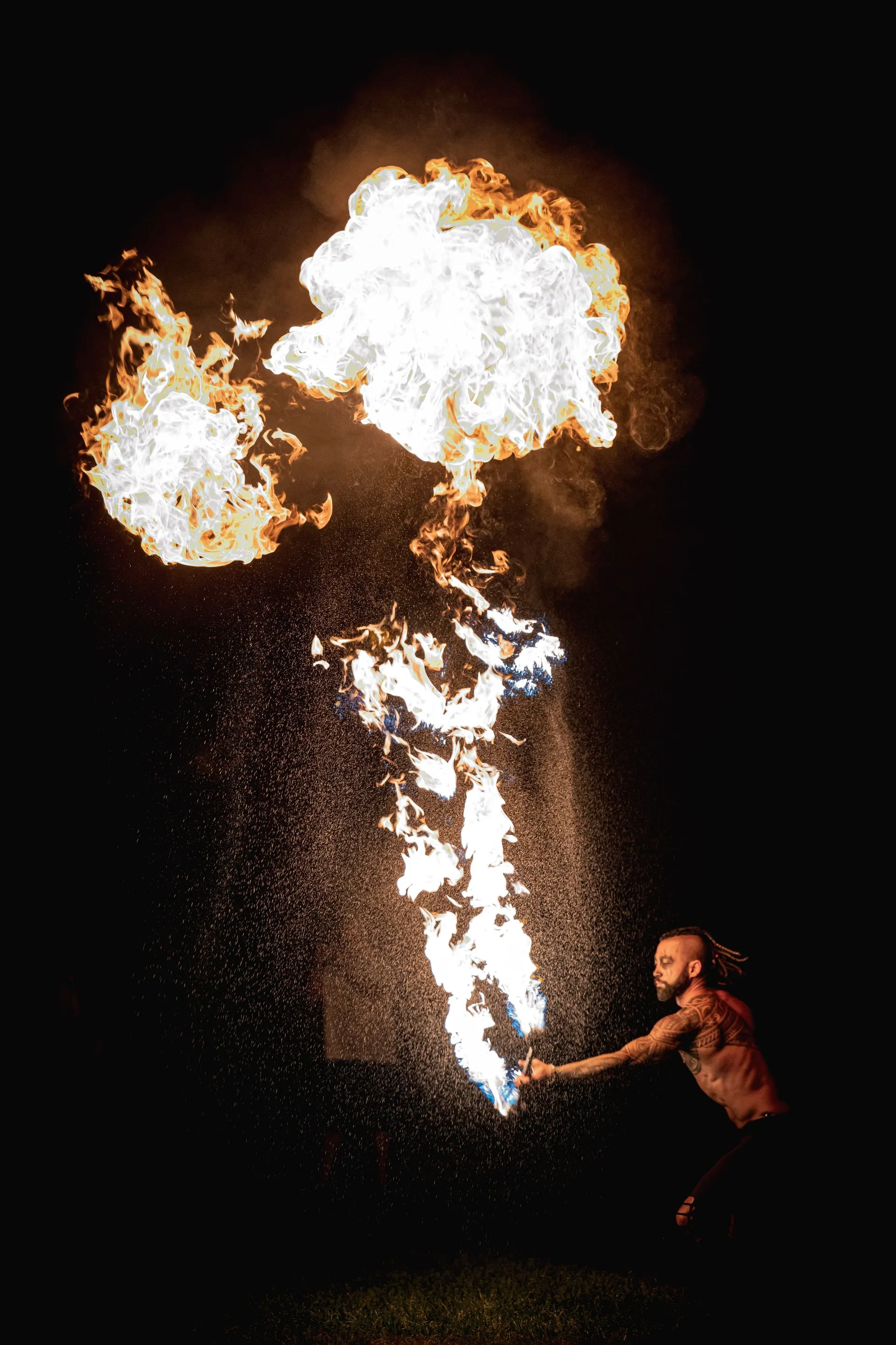 A man is standing in front of a fireball in the dark.