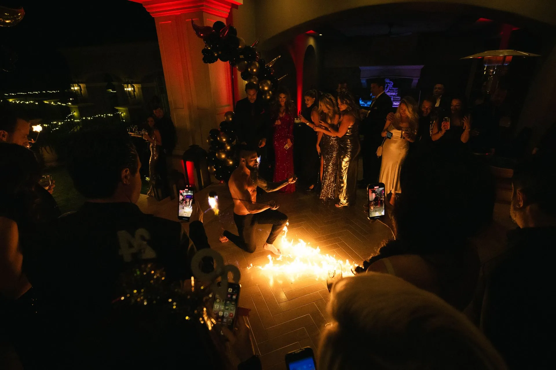 A man is kneeling down in front of a fire in a dark room.