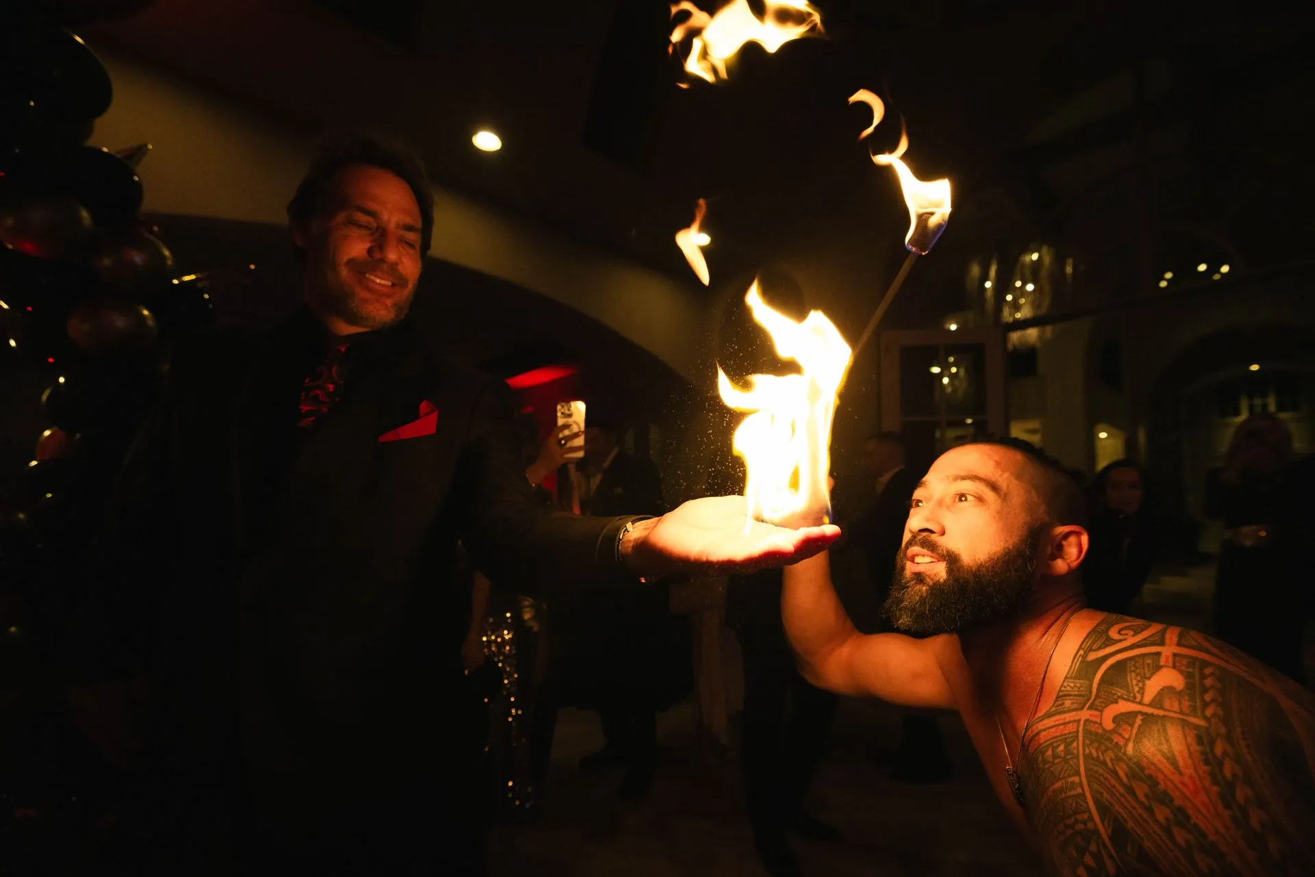 A man with a tattoo on his chest is holding a fire in his hand.