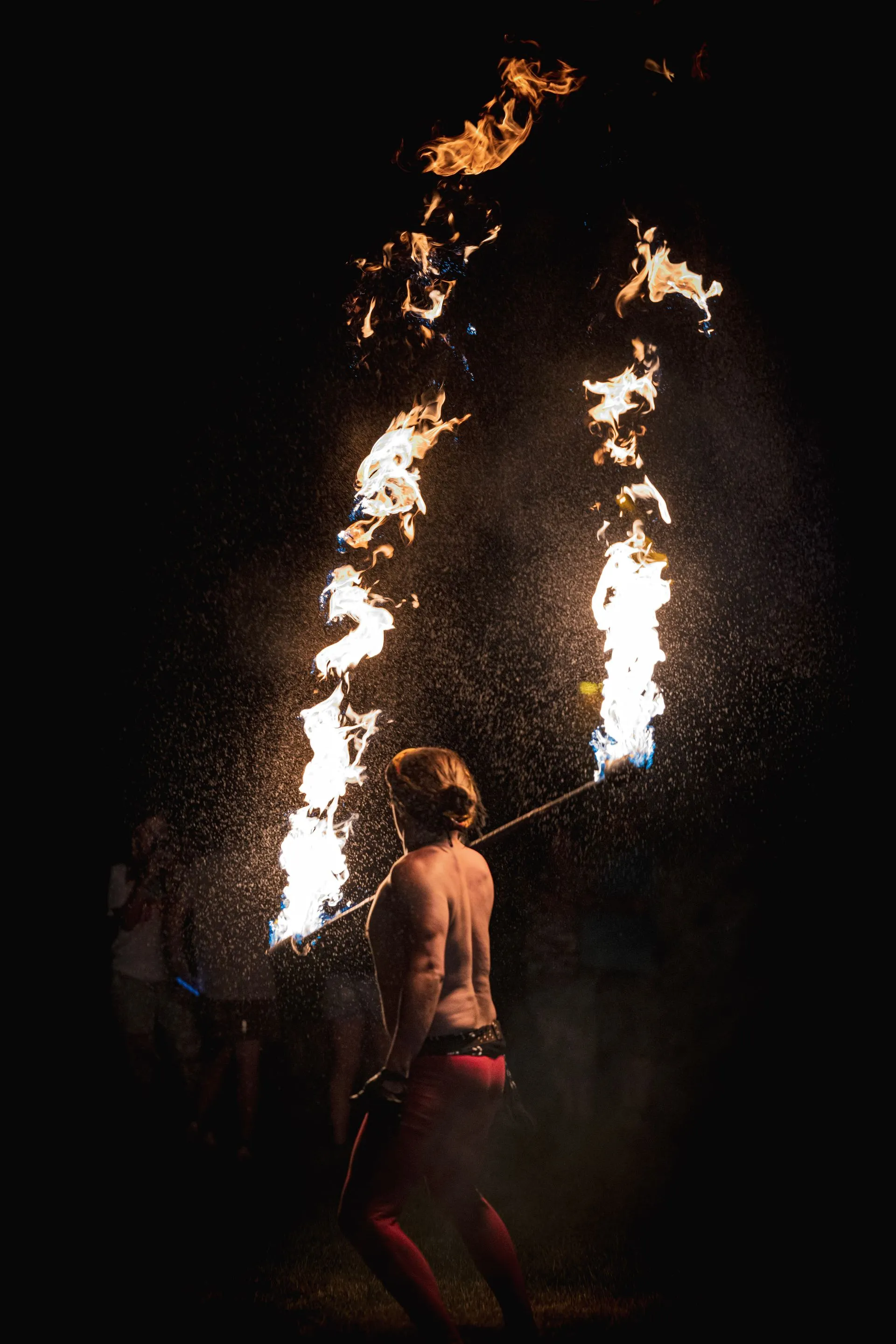 A woman is holding a stick with fire coming out of it.