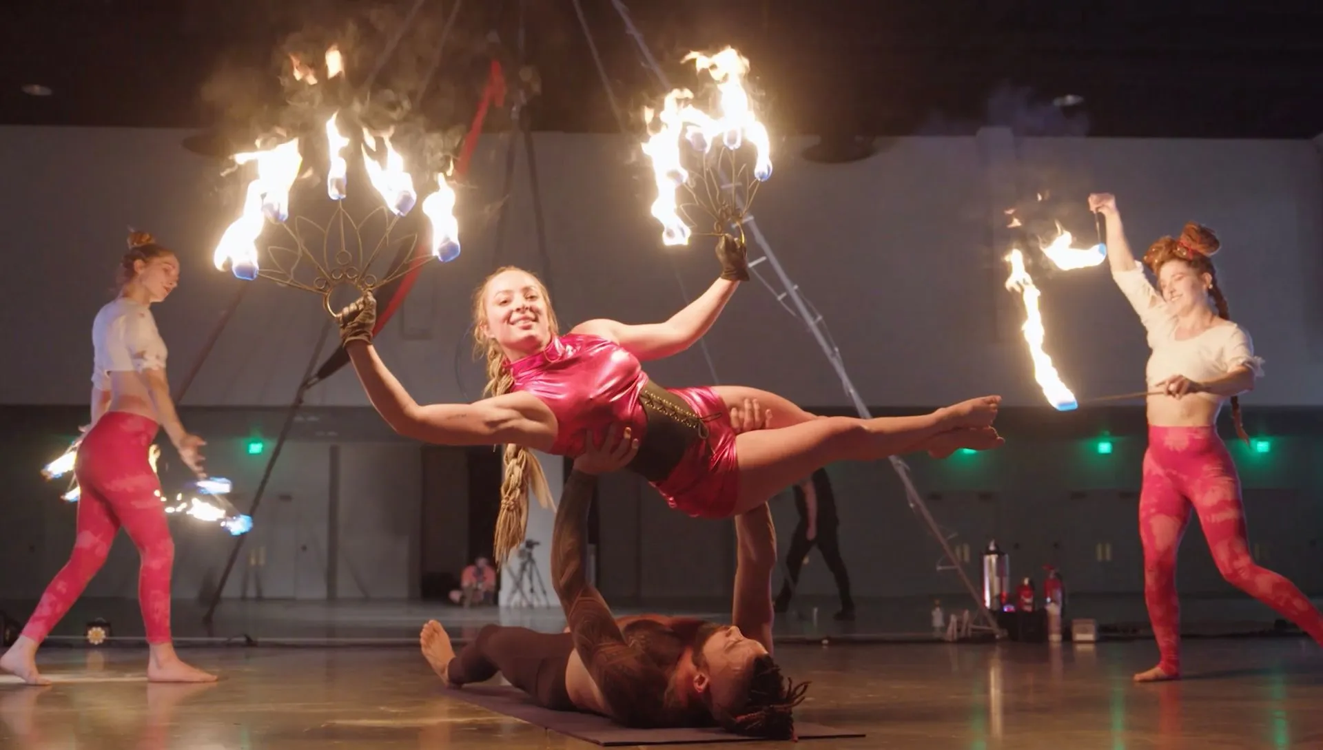 A group of people are performing aerial acrobatics with fire sticks.