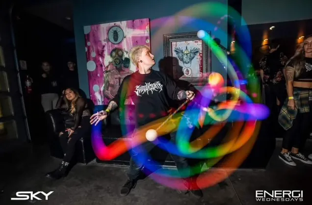 A man in a black shirt is juggling a rainbow of lights