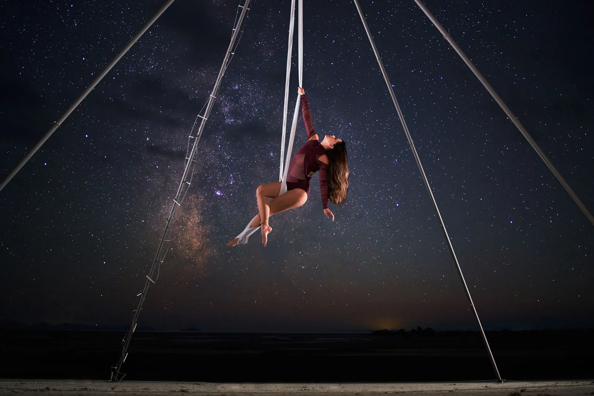 A woman is hanging from a rope in the air under a starry sky.