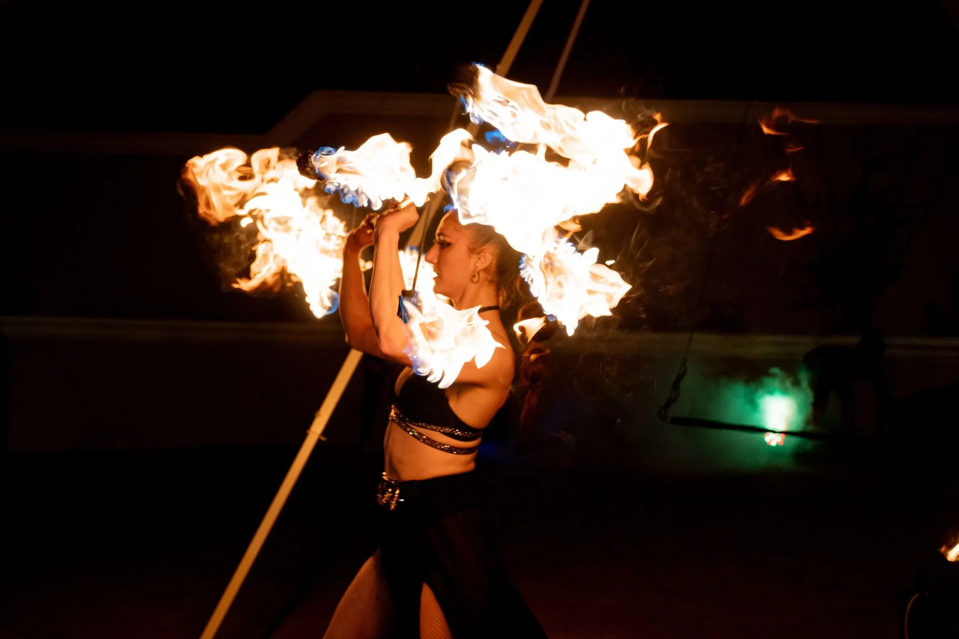 A woman is holding a stick with fire coming out of it.