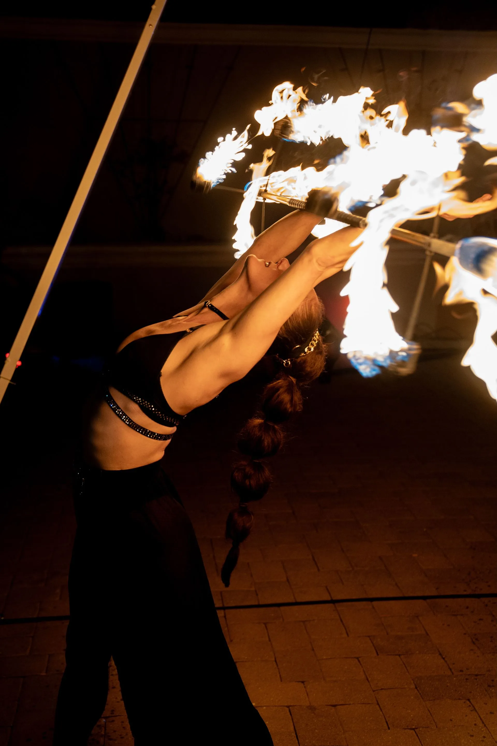 A woman is holding a stick with fire coming out of it.