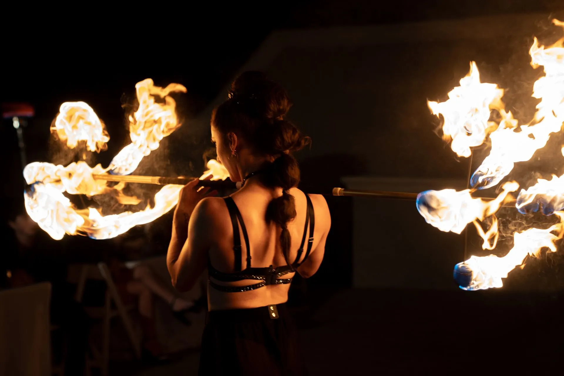 A woman is holding a stick with fire coming out of it.