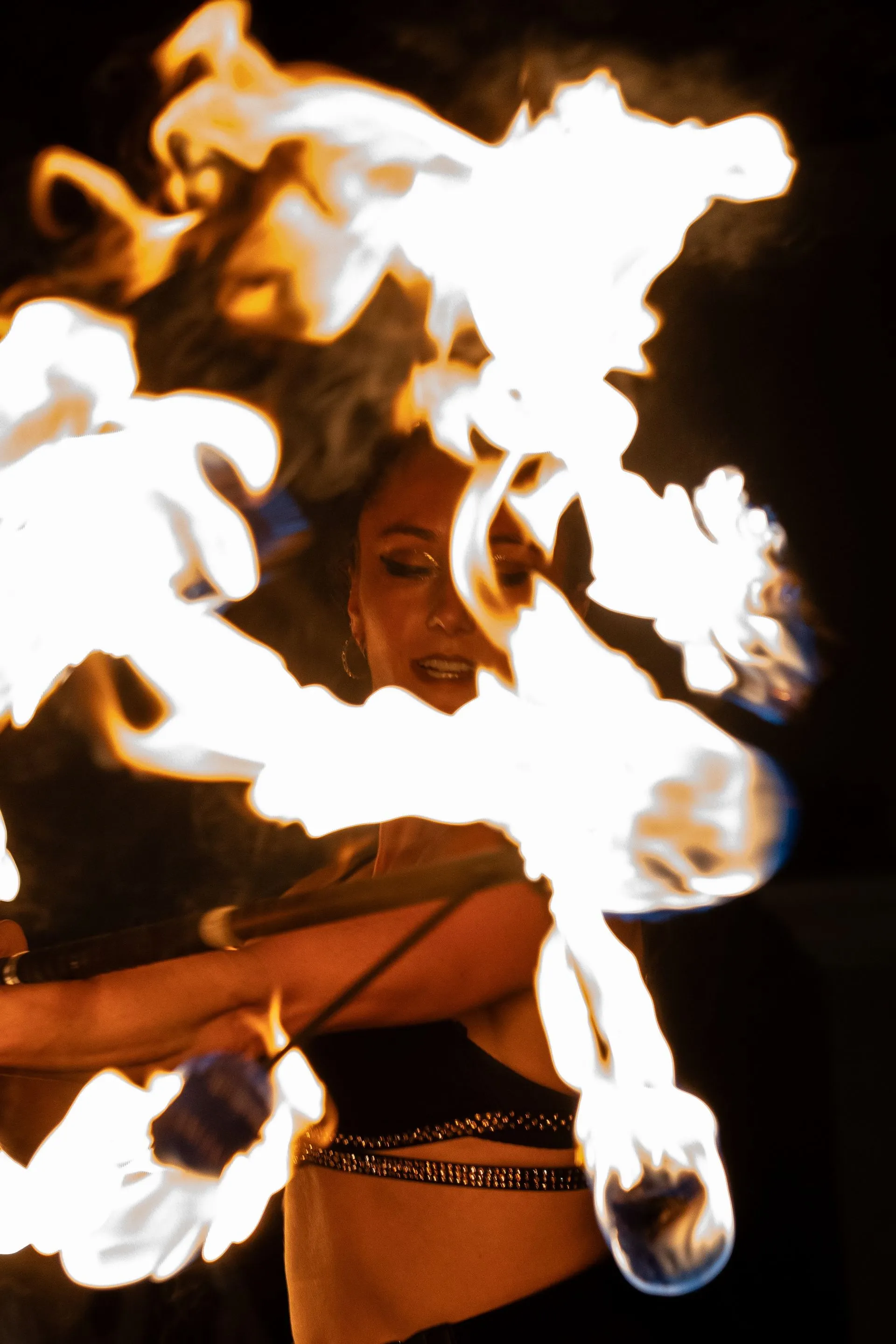 A woman is dancing with fire in her hair.