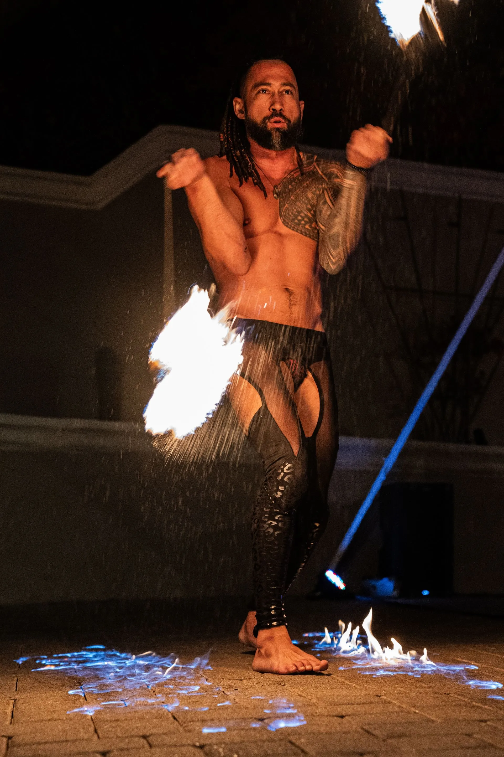 A shirtless man is holding a fire stick in his hand