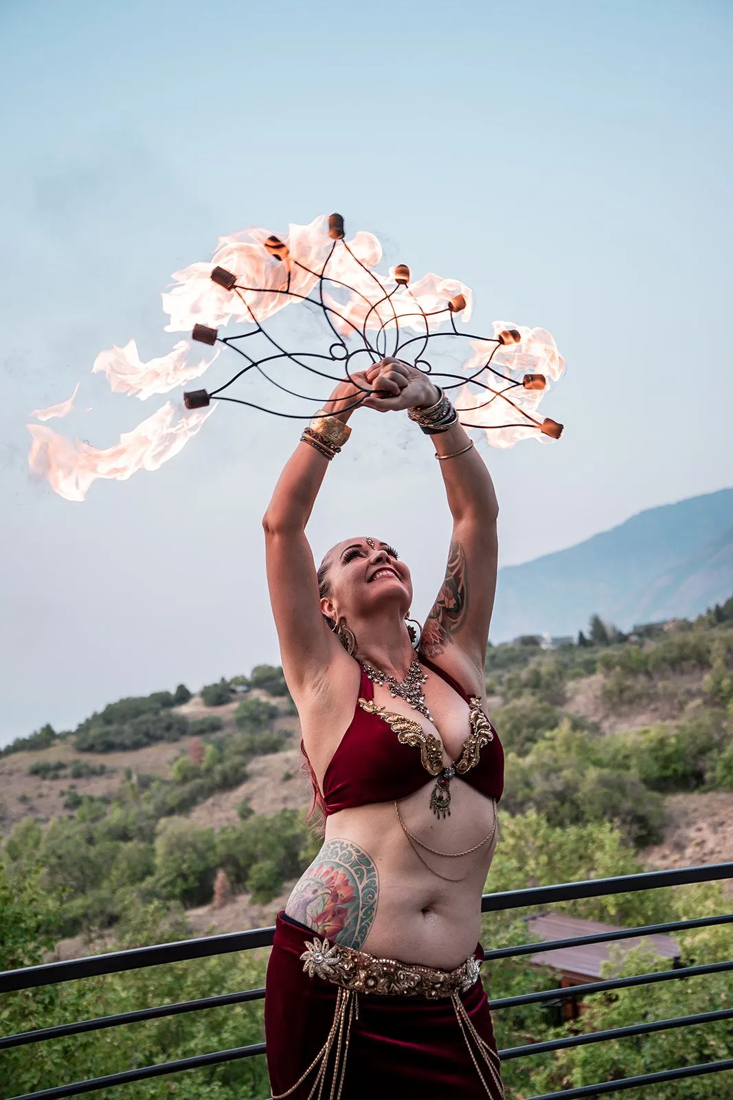 A belly dancer is holding a fan of fire in her hands.