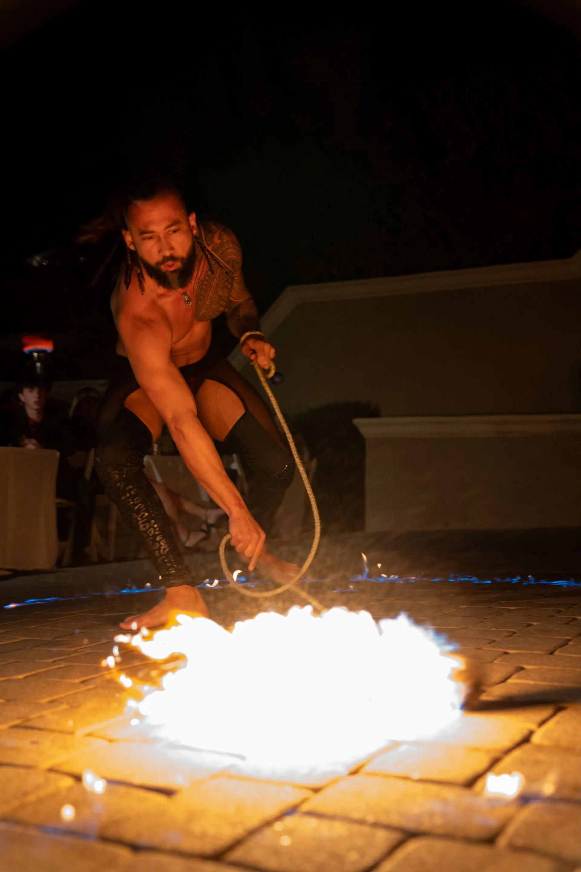 A man is holding a rope in front of a fire.