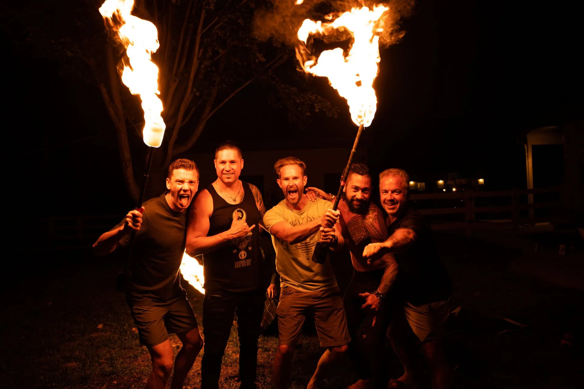 A group of men are posing for a picture with fire torches.