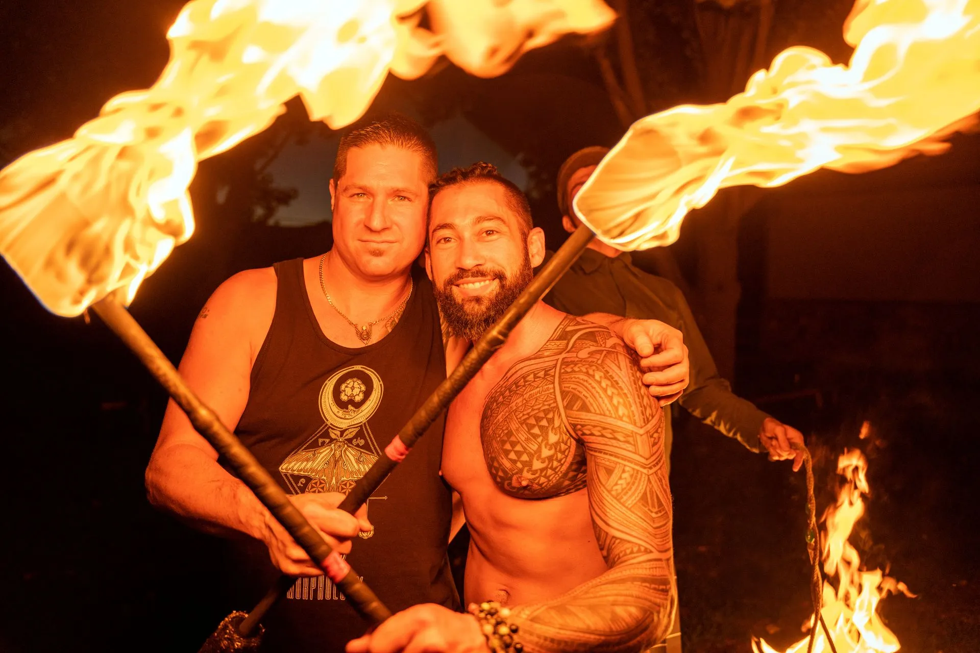 Two men are holding fire torches in their hands and posing for a picture.