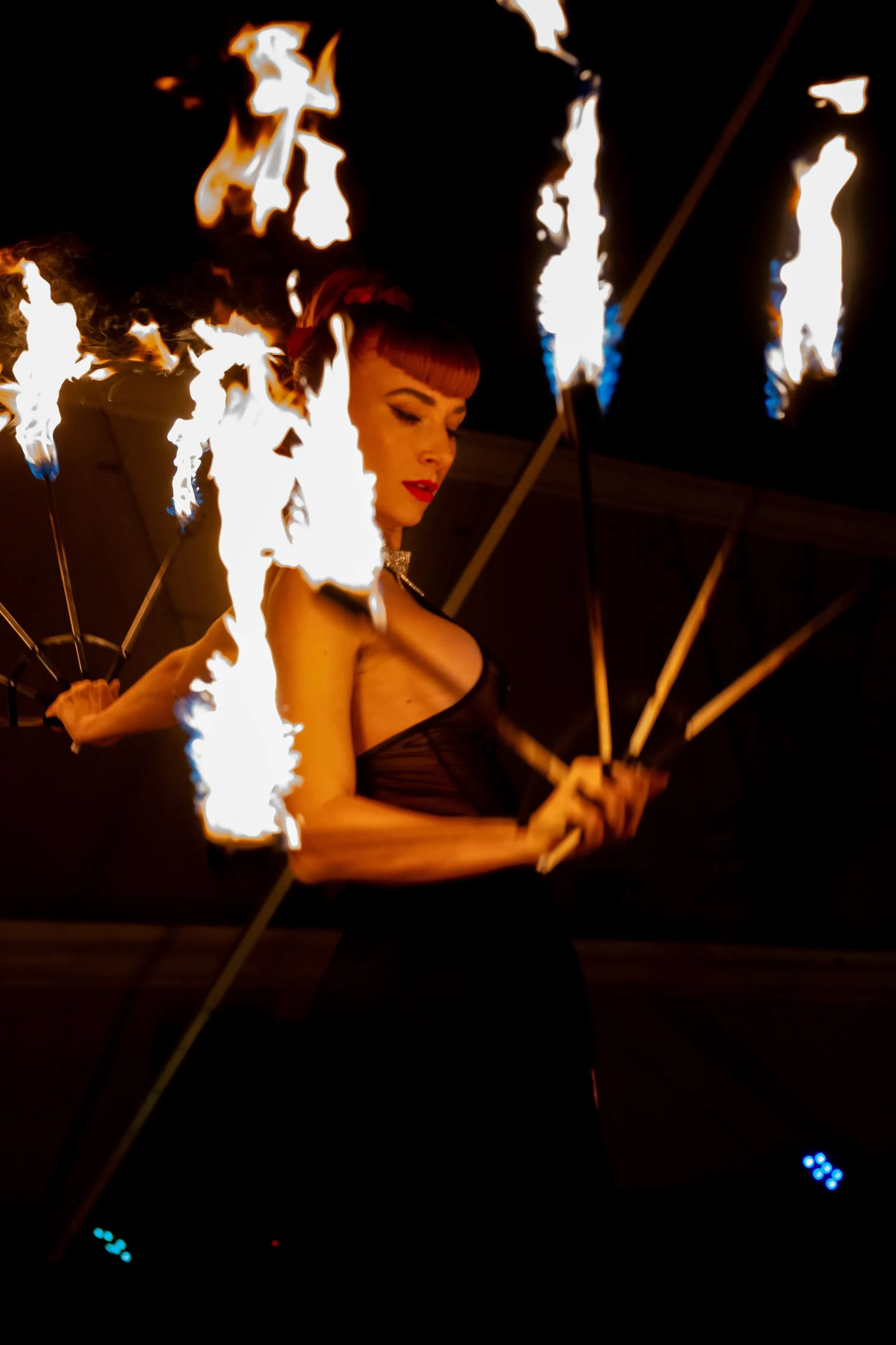 A woman in a black dress is holding a torch with flames coming out of it