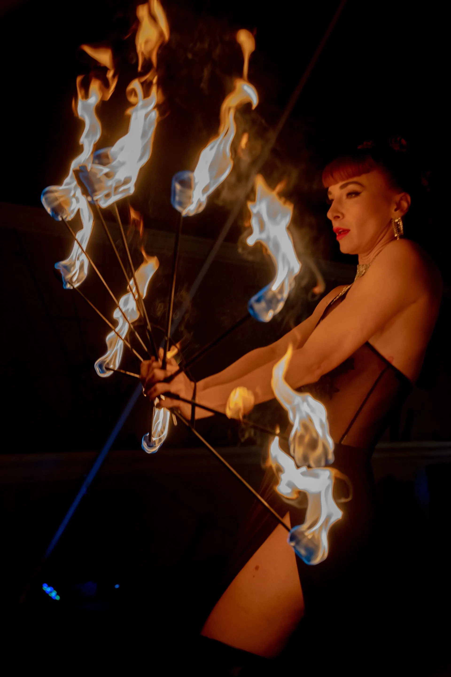 A woman in a black dress is holding a bunch of flames.