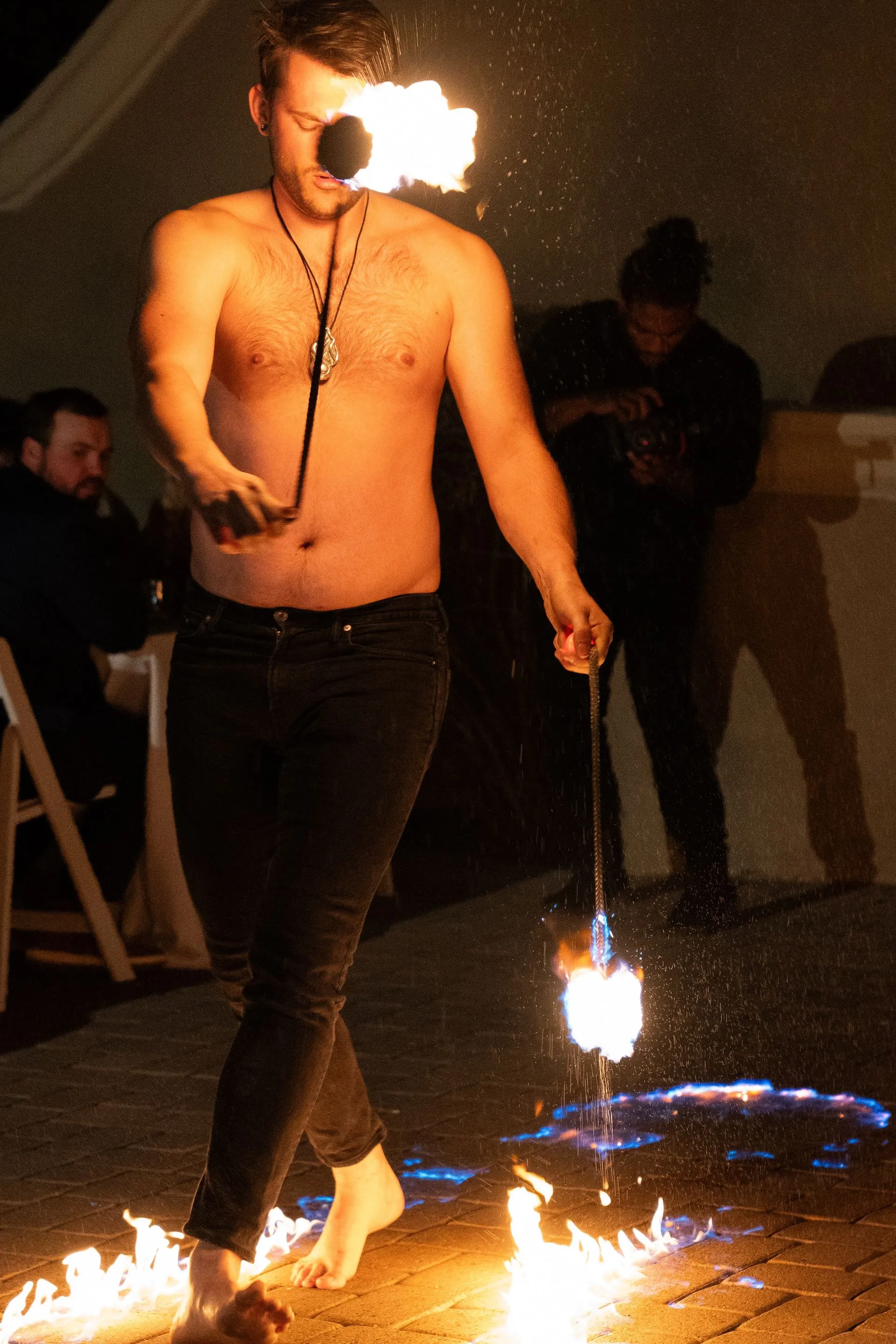 A shirtless man is walking through a circle of fire.