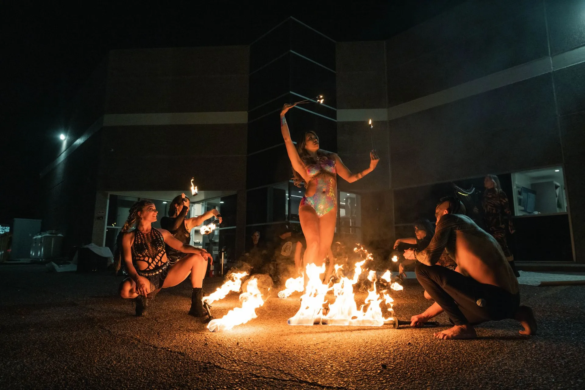 A group of people are sitting around a fire at night.