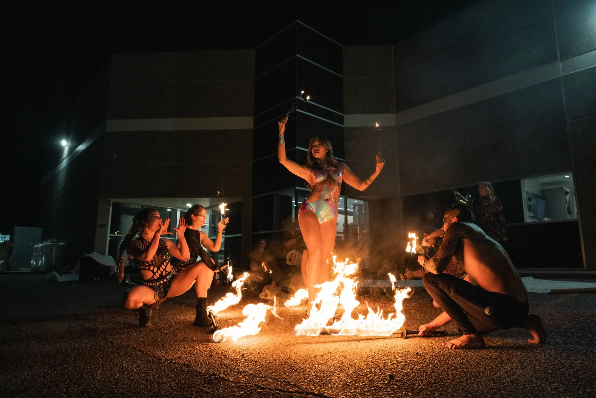 A group of people are standing around a fire at night.