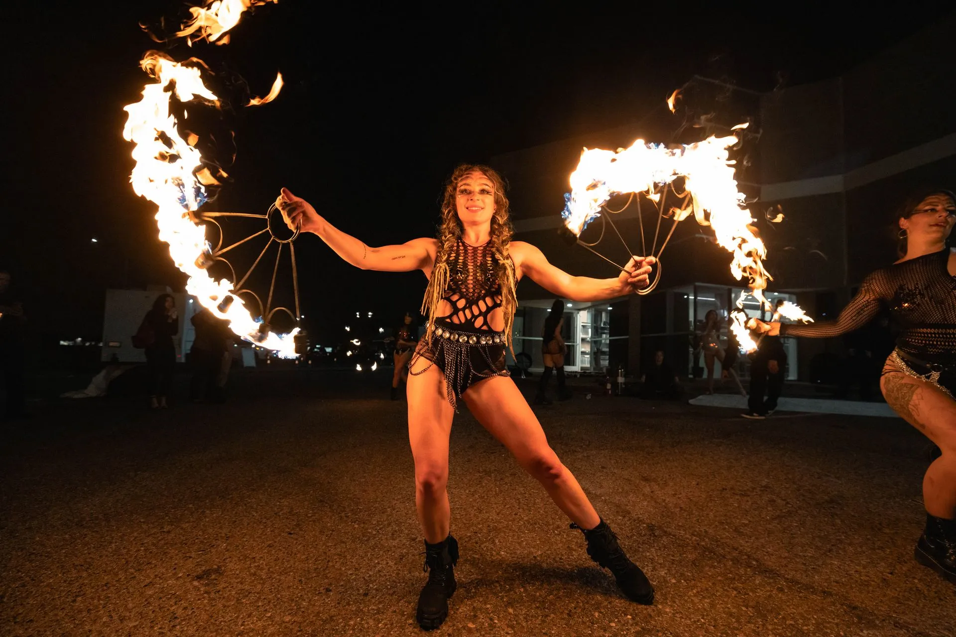 A woman is holding a pair of fire fans in her hands.