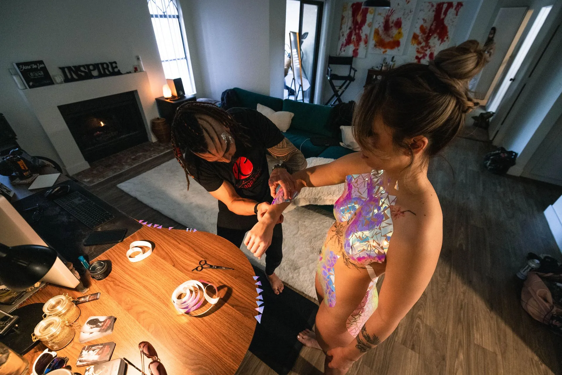 A man creating body tape decoration for a female model.