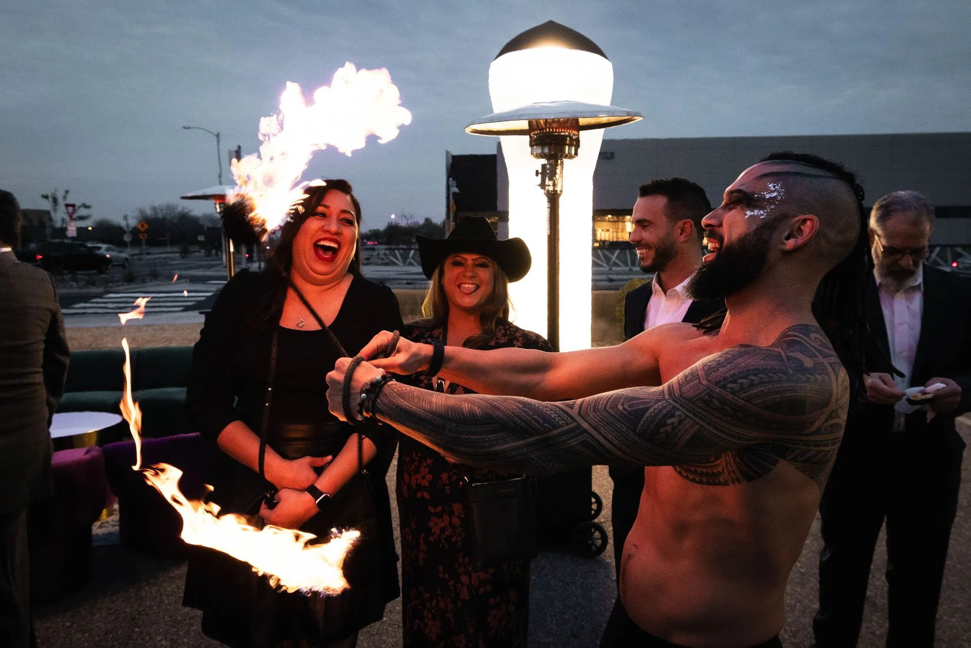 A man without a shirt is holding a torch with flames coming out of it.