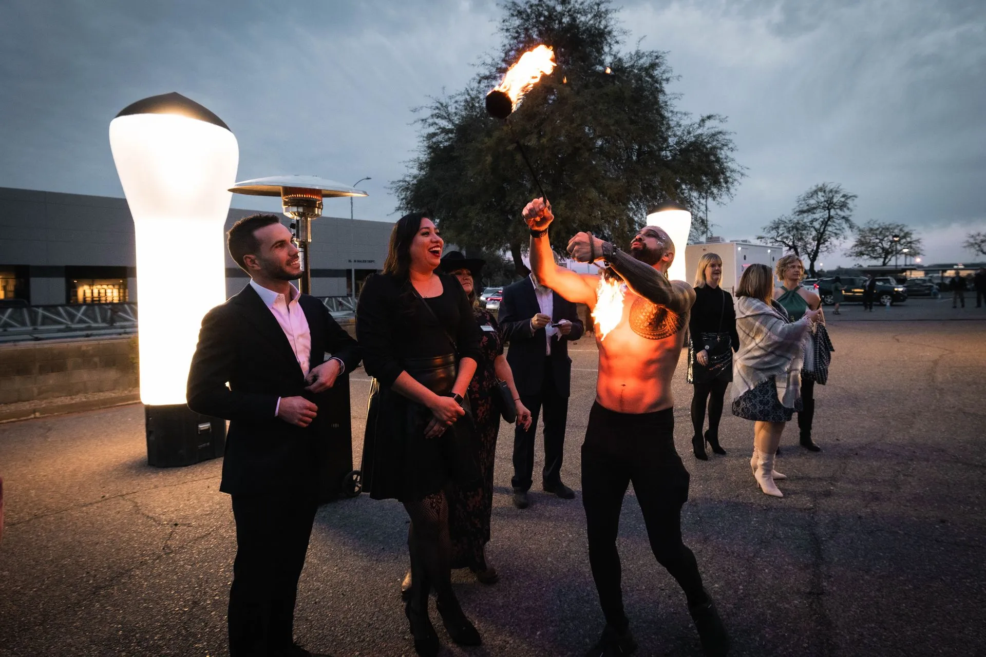 A group of people are standing around a man holding a fire torch.