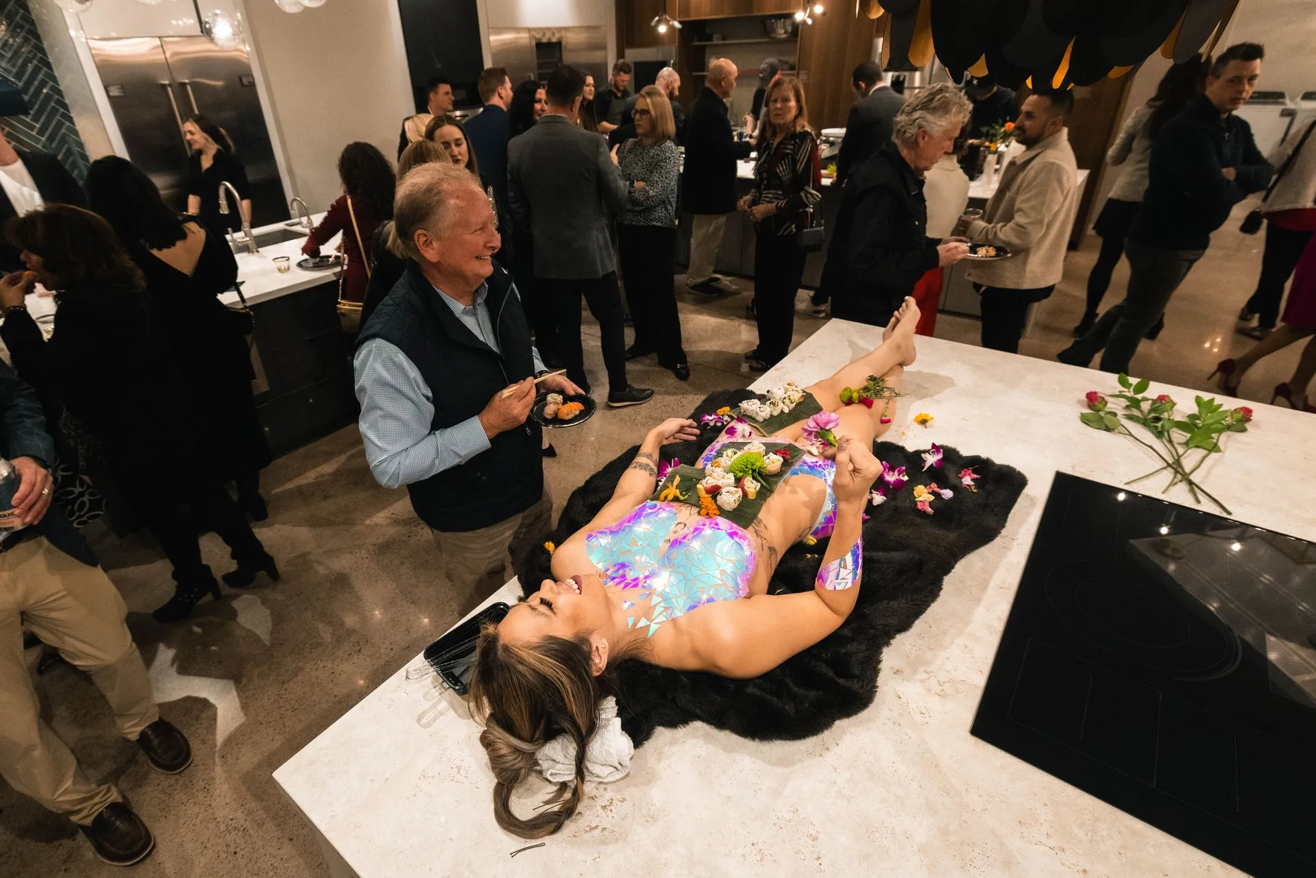 A woman is laying on a table with sushi on her body.