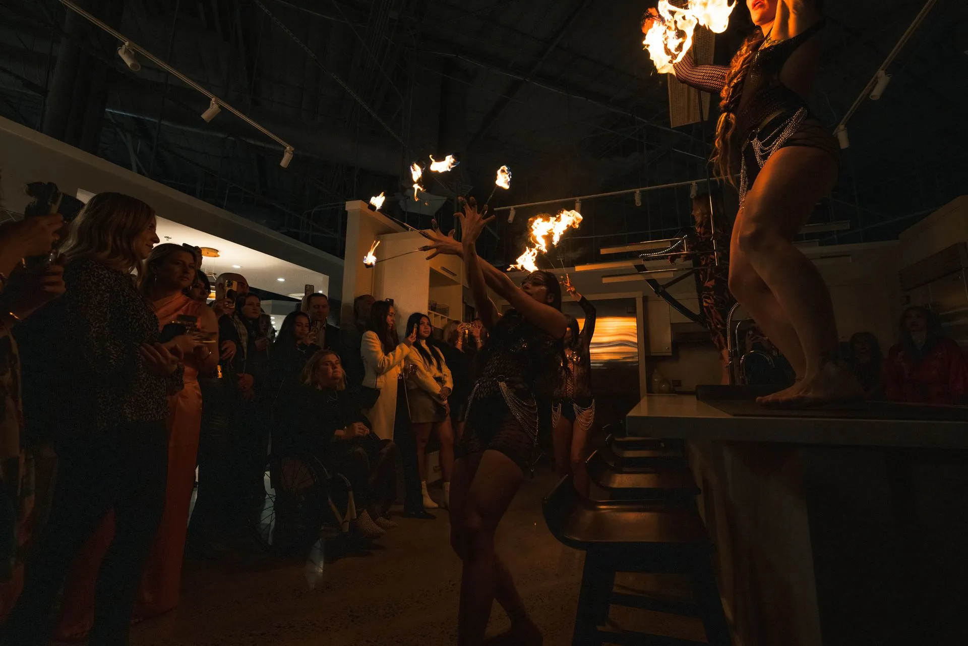 A group of people are standing in a dark room watching a fire show.