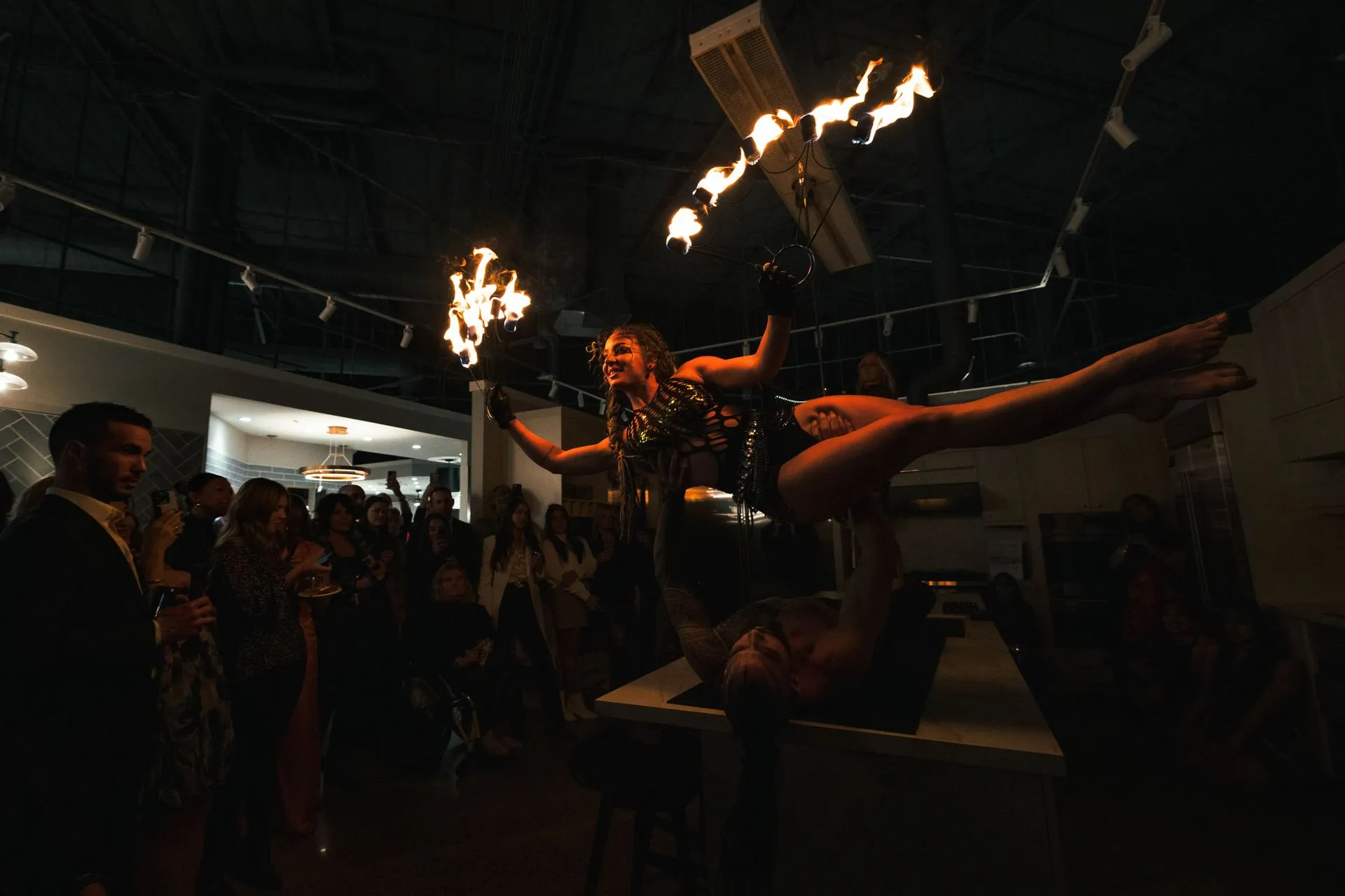 A group of people are watching a fire performance in a dark room.