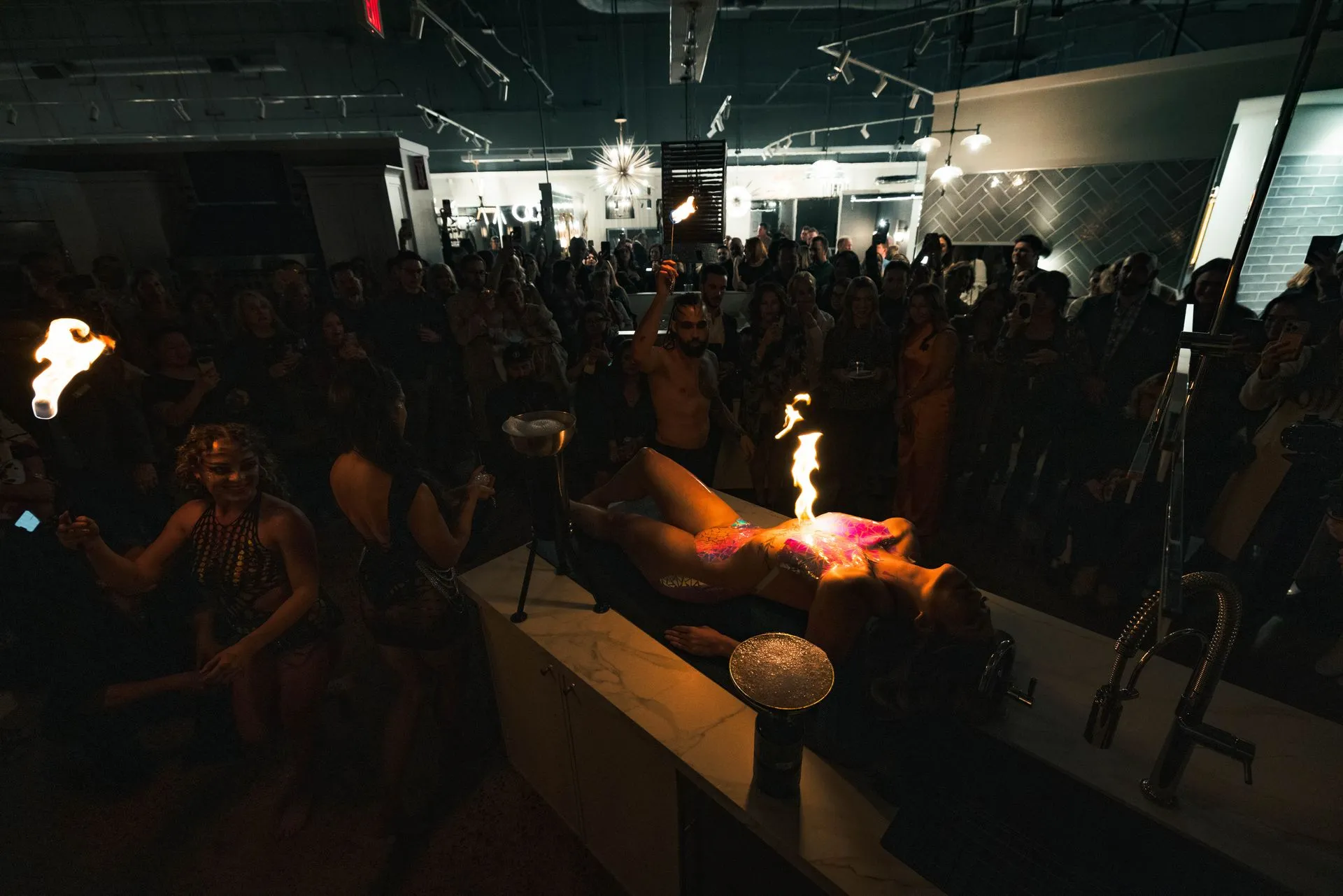 A woman is laying on a table in front of a crowd of people.