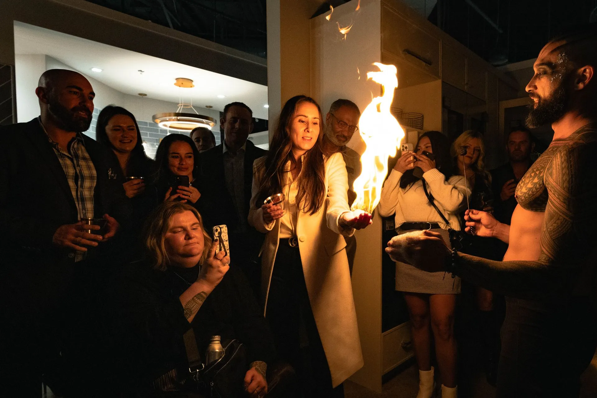 A group of people are standing around a man holding a fireball.