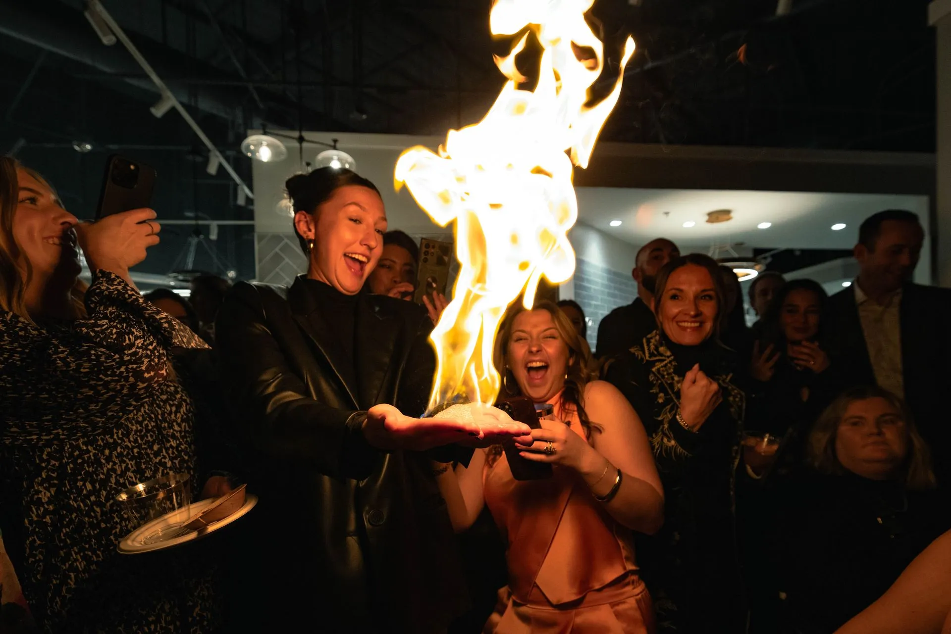 A woman is holding a piece of cake with flames coming out of it.