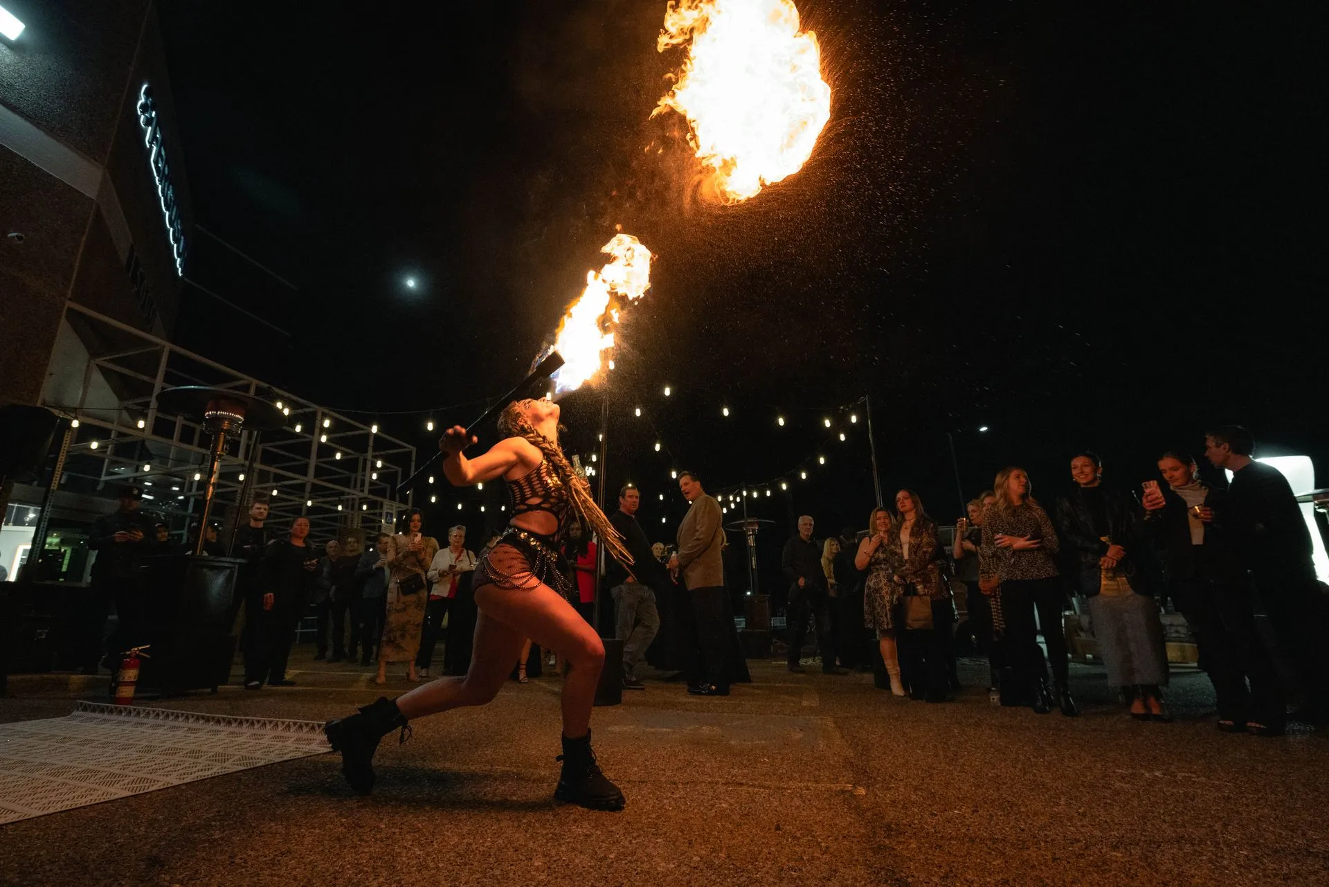 A woman is blowing fire out of her mouth at a party.