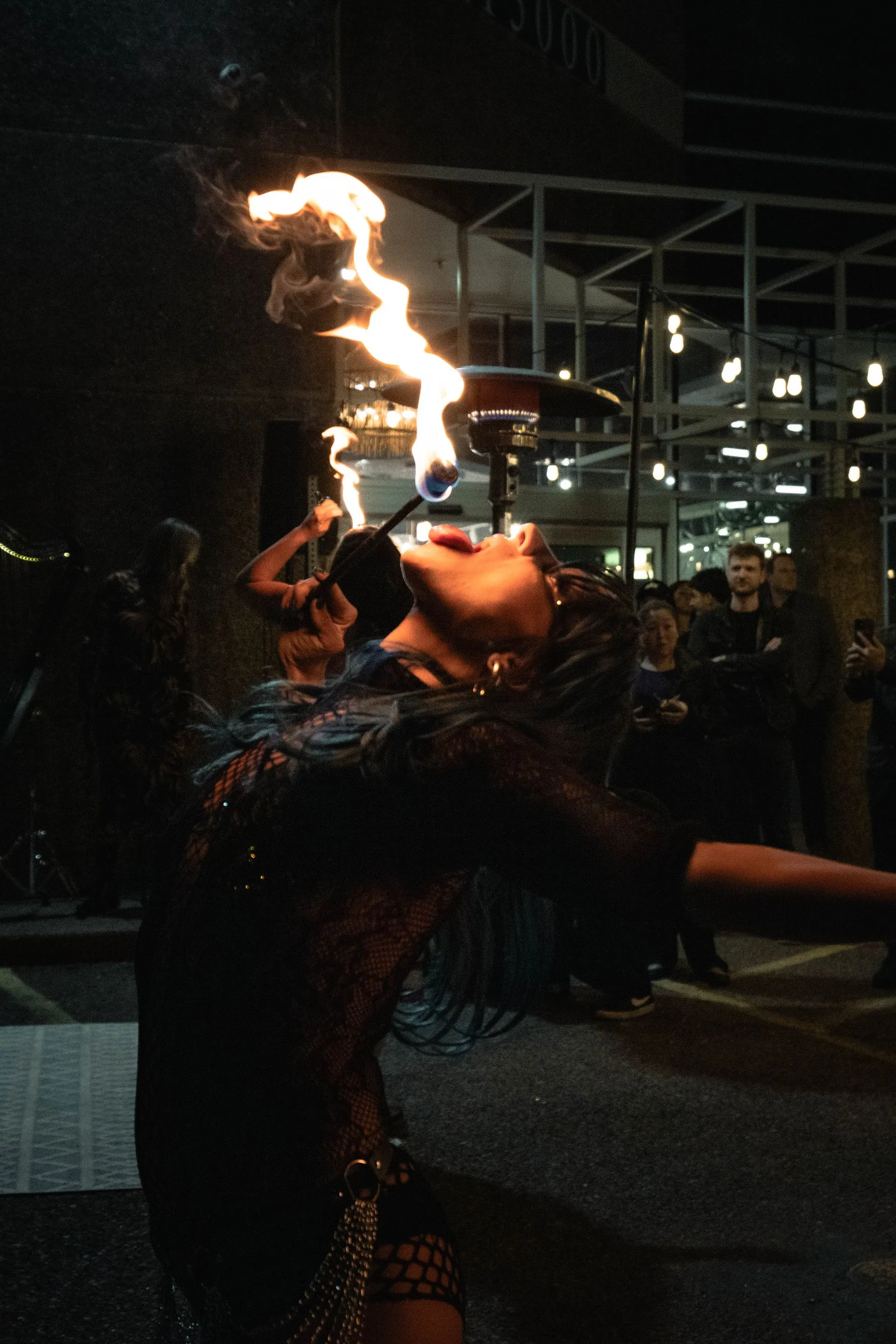 A woman is blowing flames out of her mouth at night