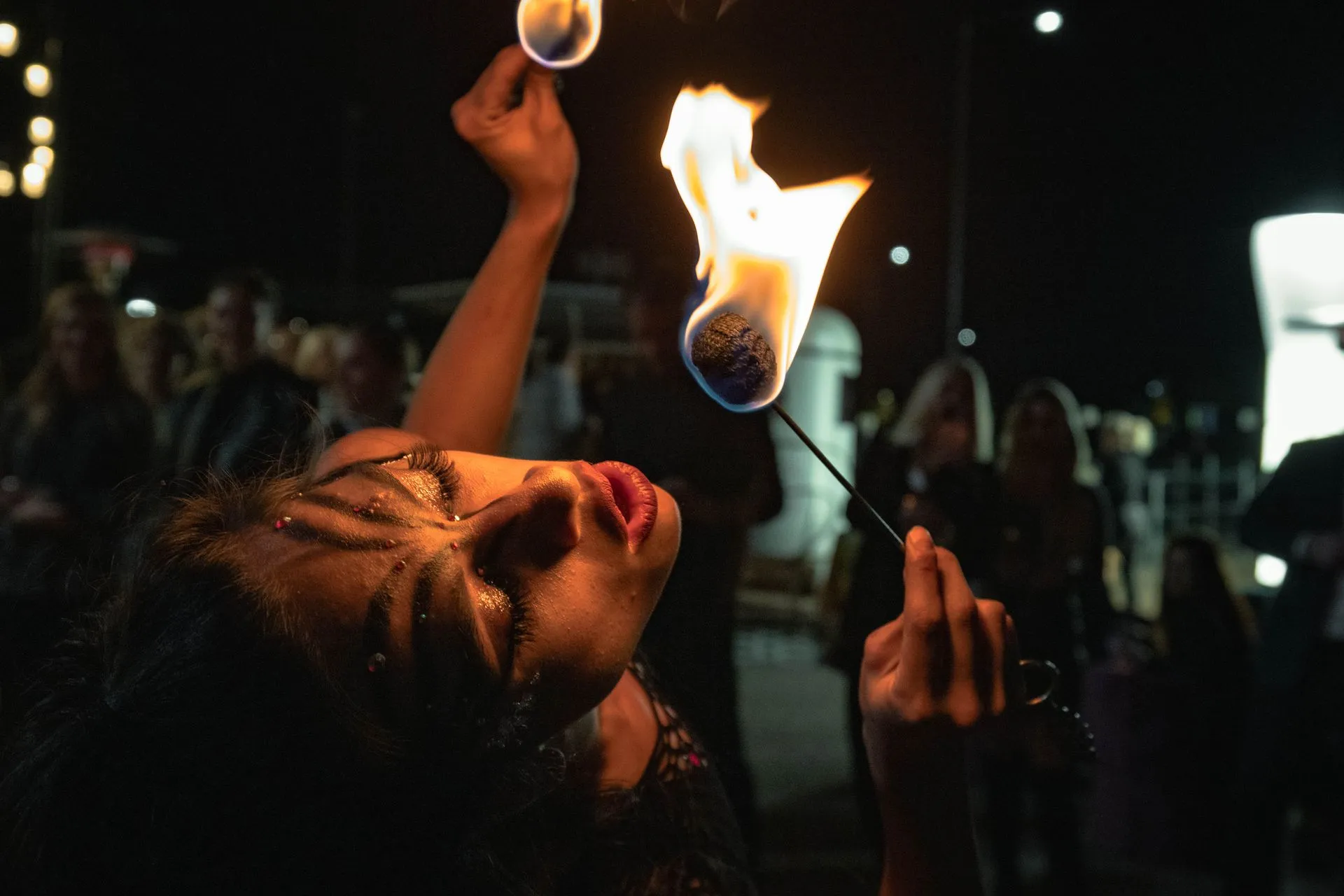 A woman is holding a stick with a fireball in her mouth.