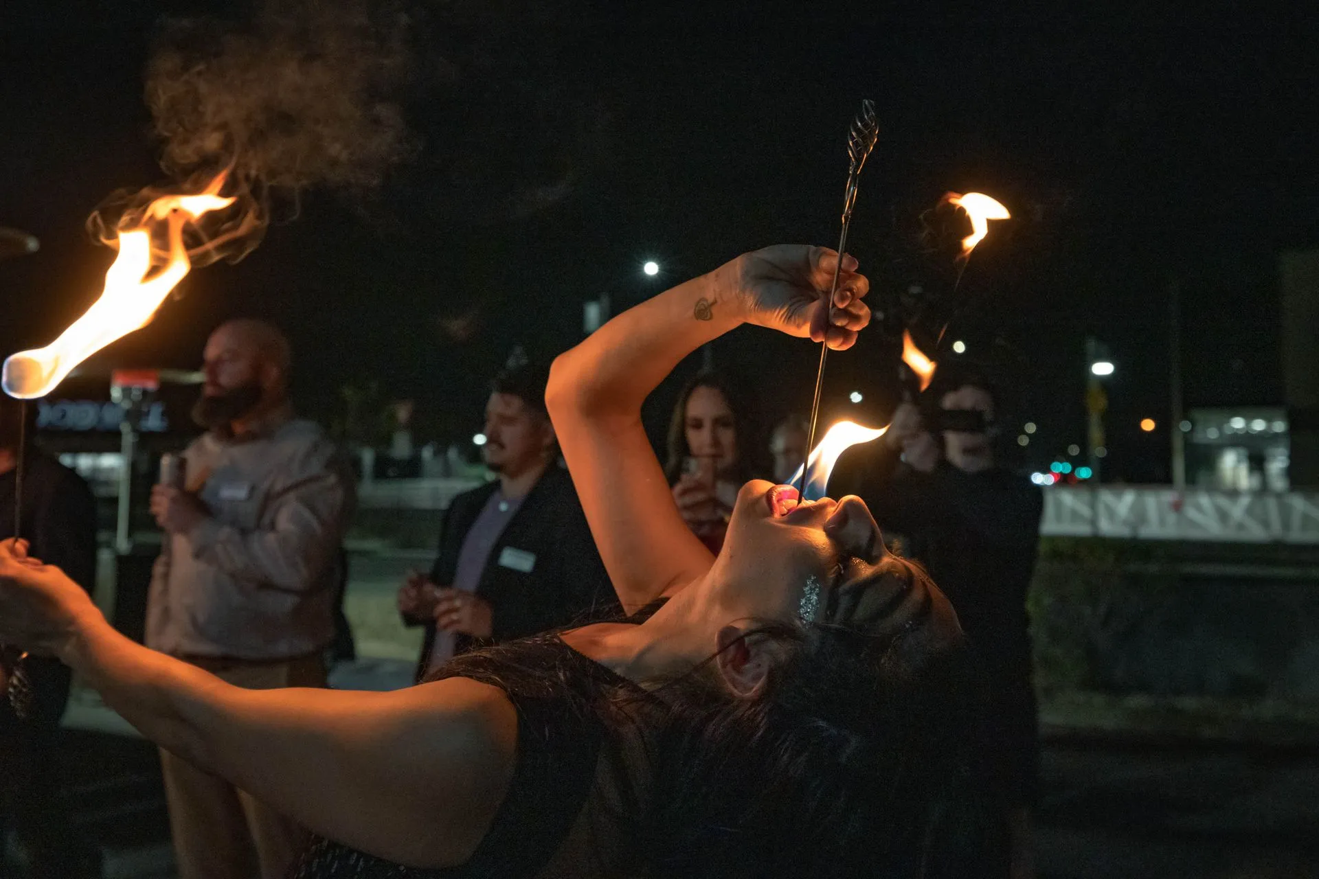 A woman is holding a torch in her mouth and drinking from it.