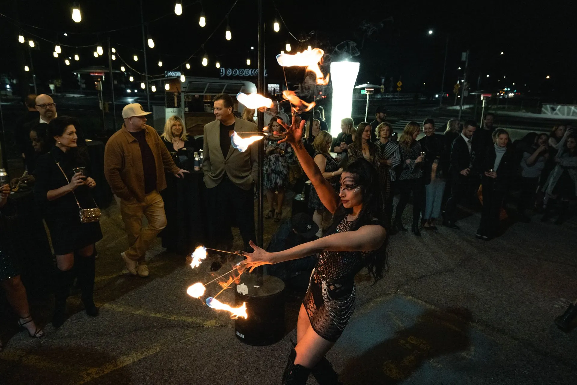 A woman is dancing with fire in front of a crowd of people.