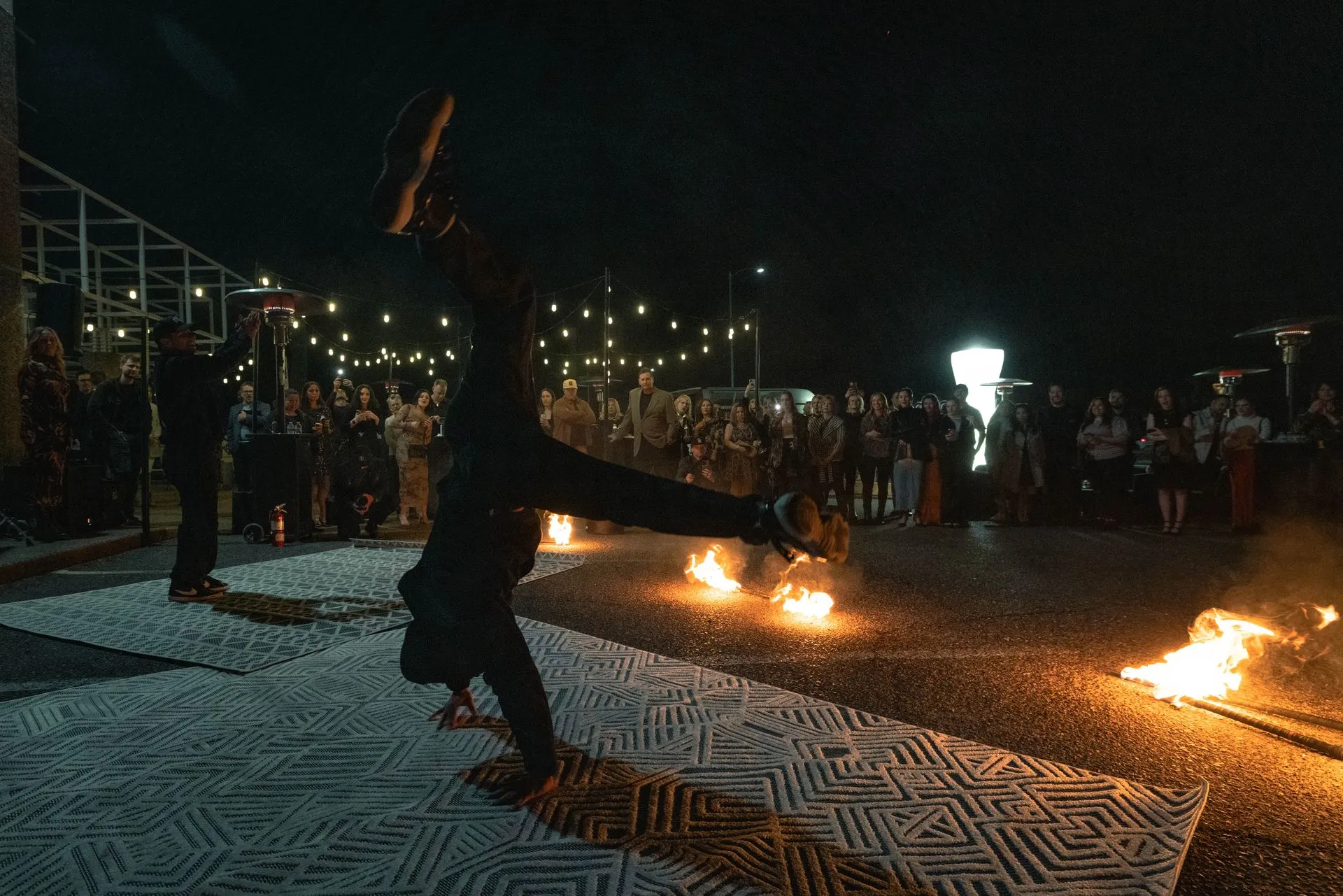 A person is doing a trick with fire in front of a crowd at night.