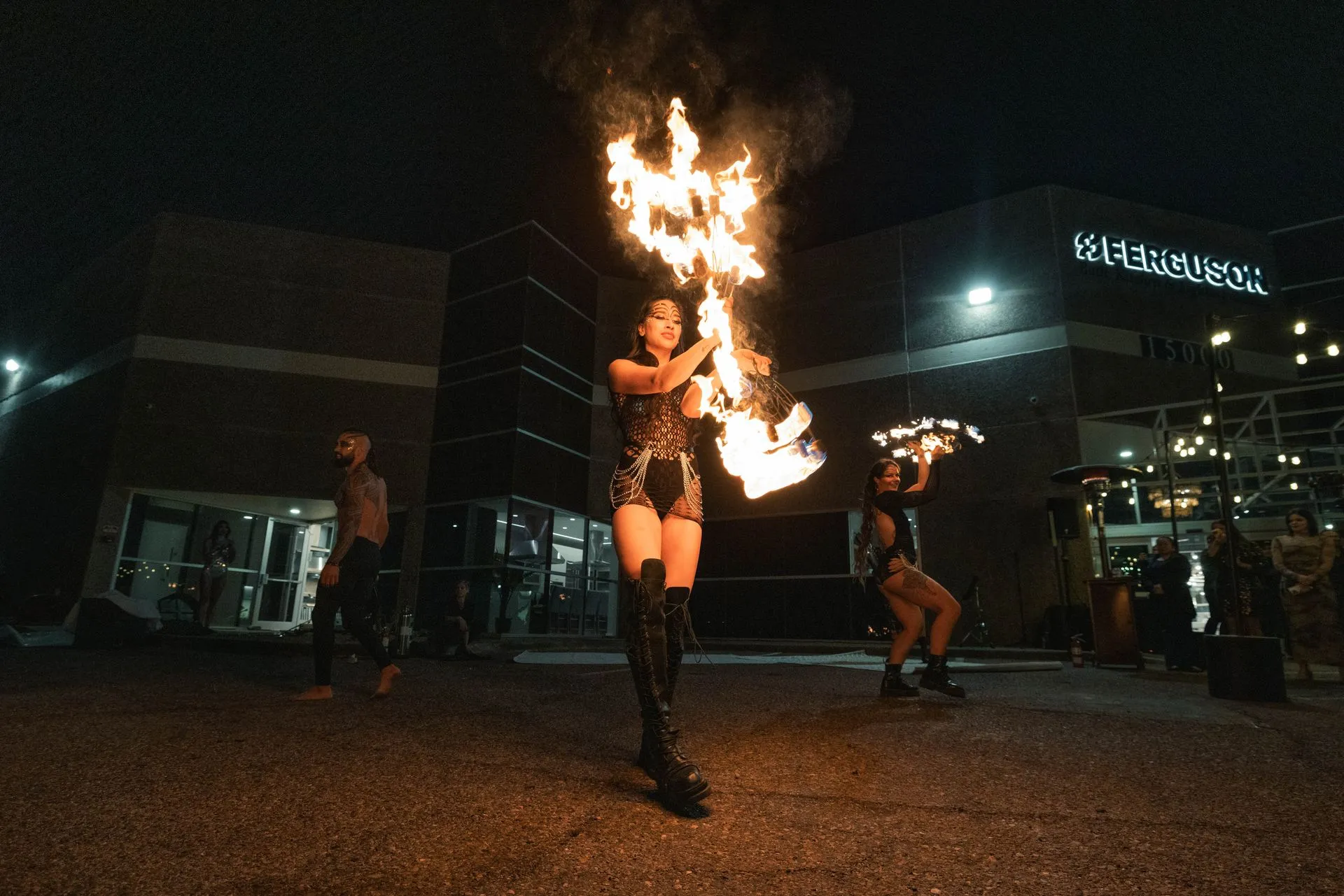 A woman is holding a fireball in front of a building at night.