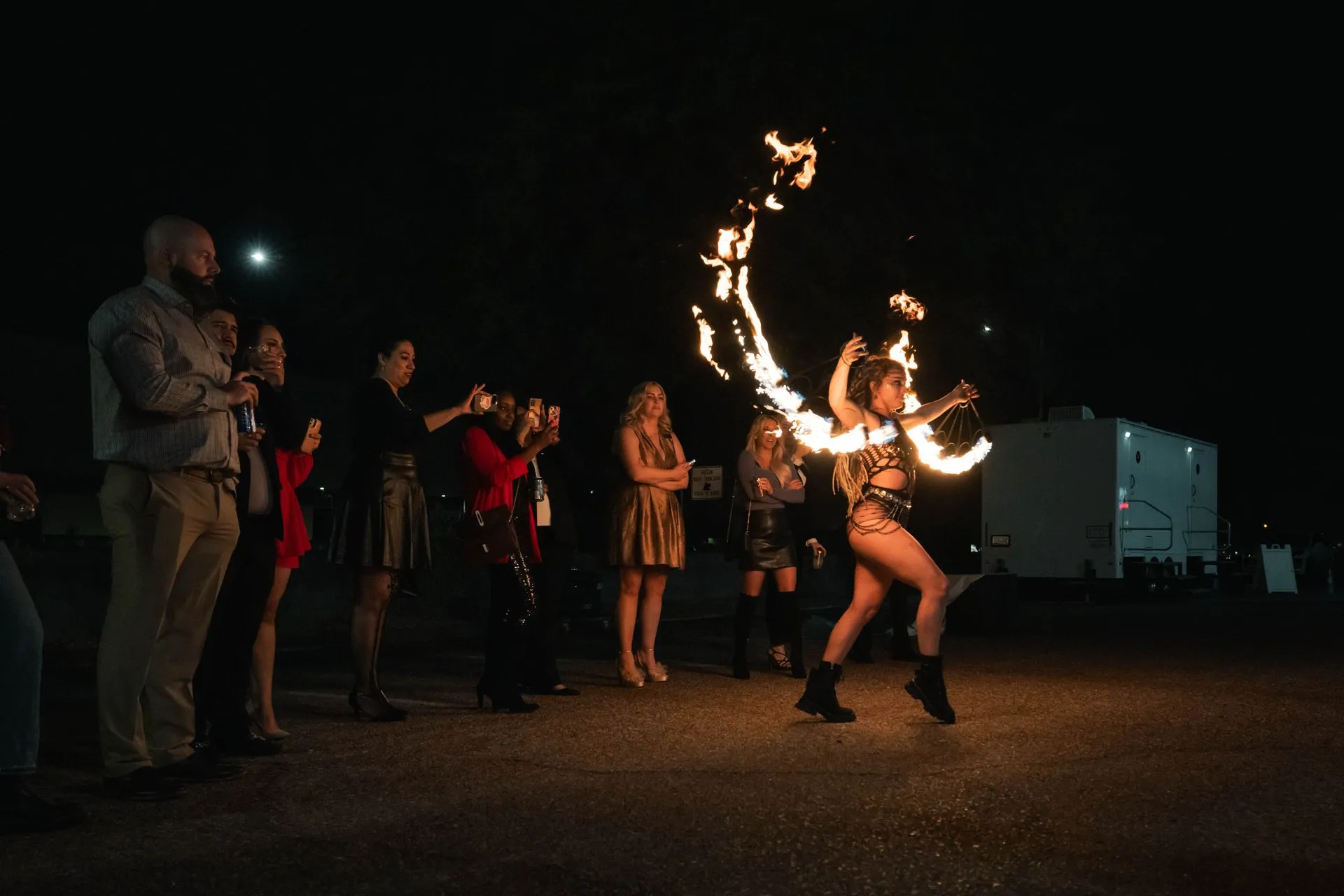 A woman is dancing with fire in her hands in front of a crowd of people.