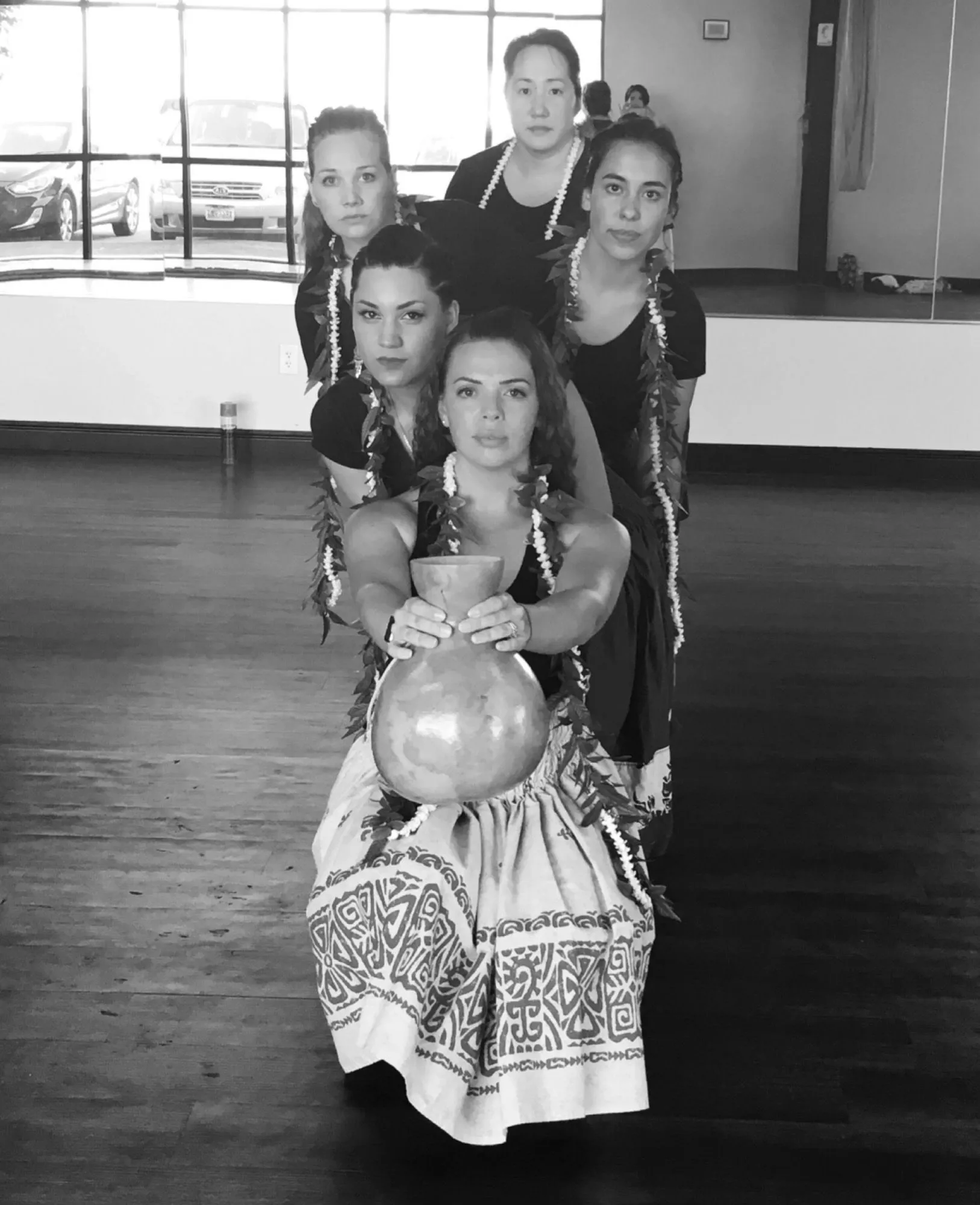 A black and white photo of a group of women holding a vase