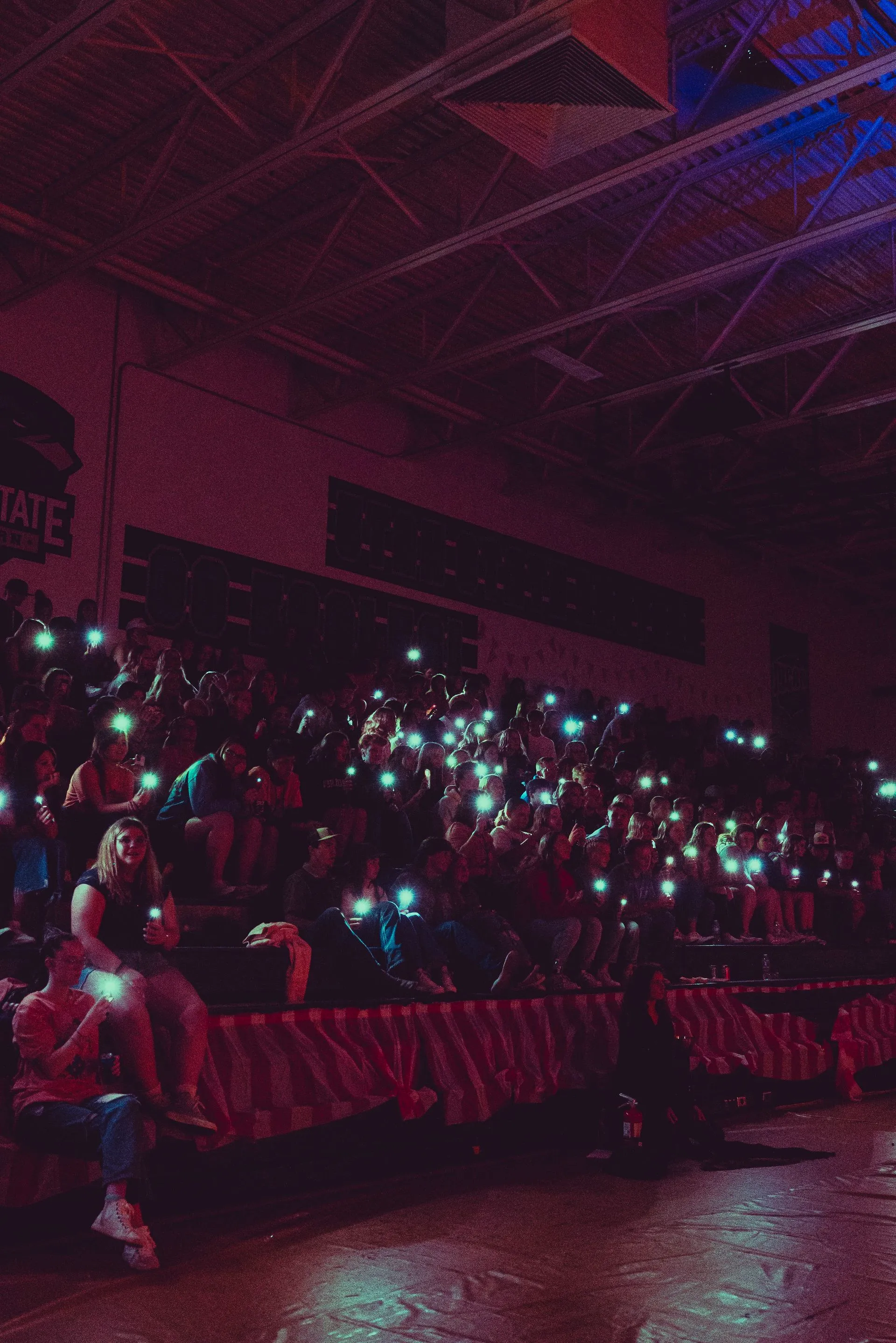 A crowd of people are sitting in a stadium with their phones in their hands.