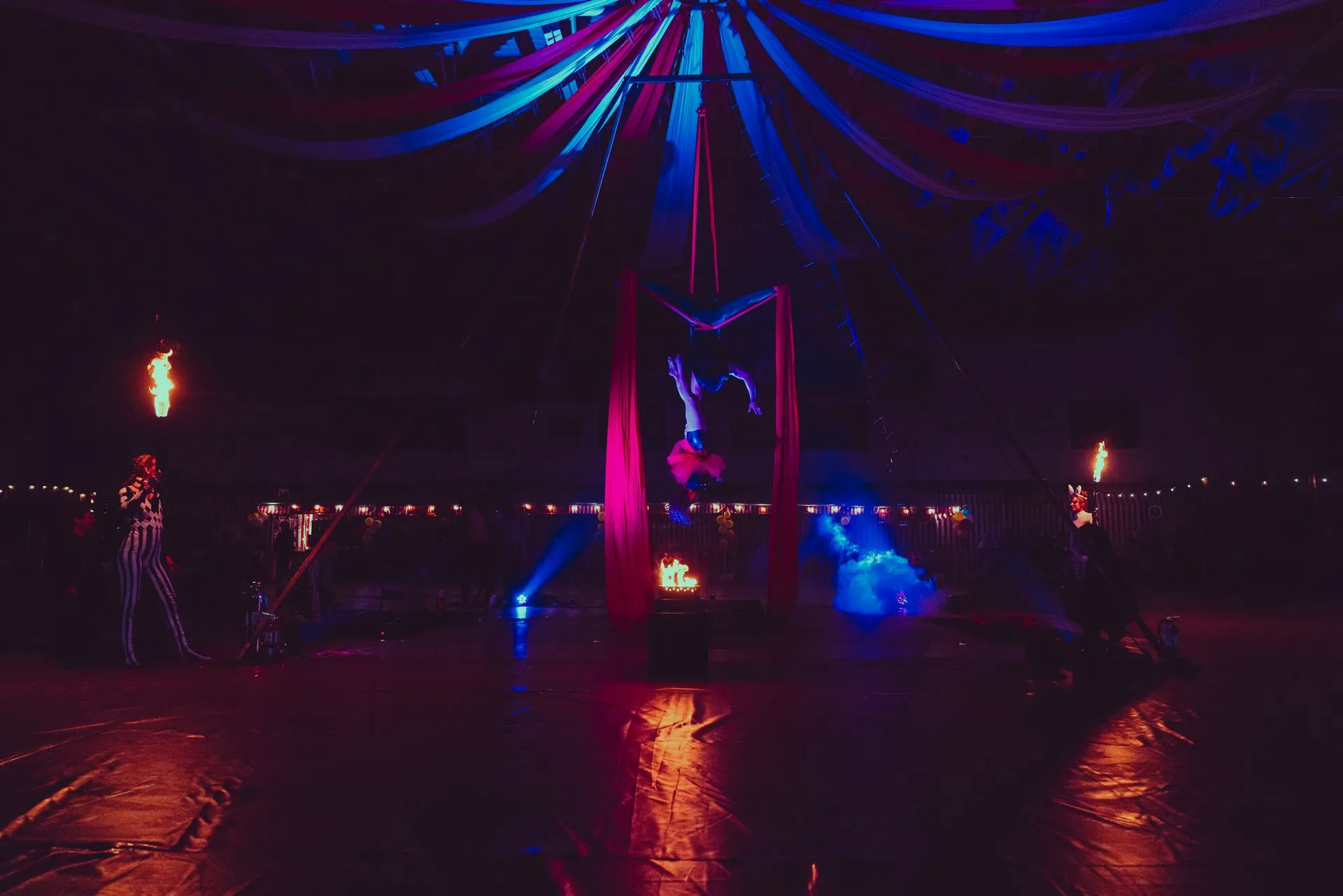 A woman is doing a handstand in a circus tent at night.
