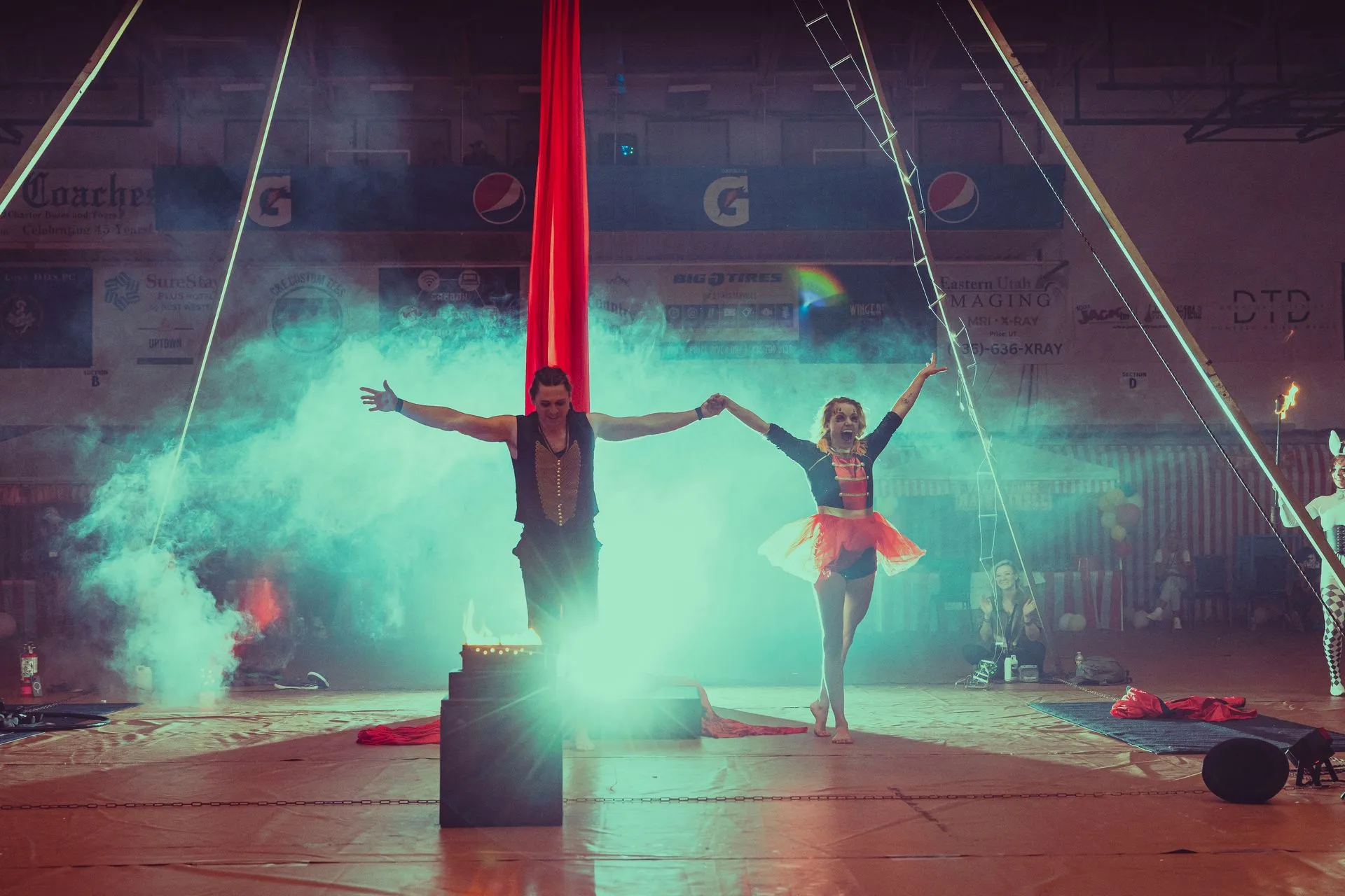 A man and a woman are performing aerial acrobatics in a circus tent.