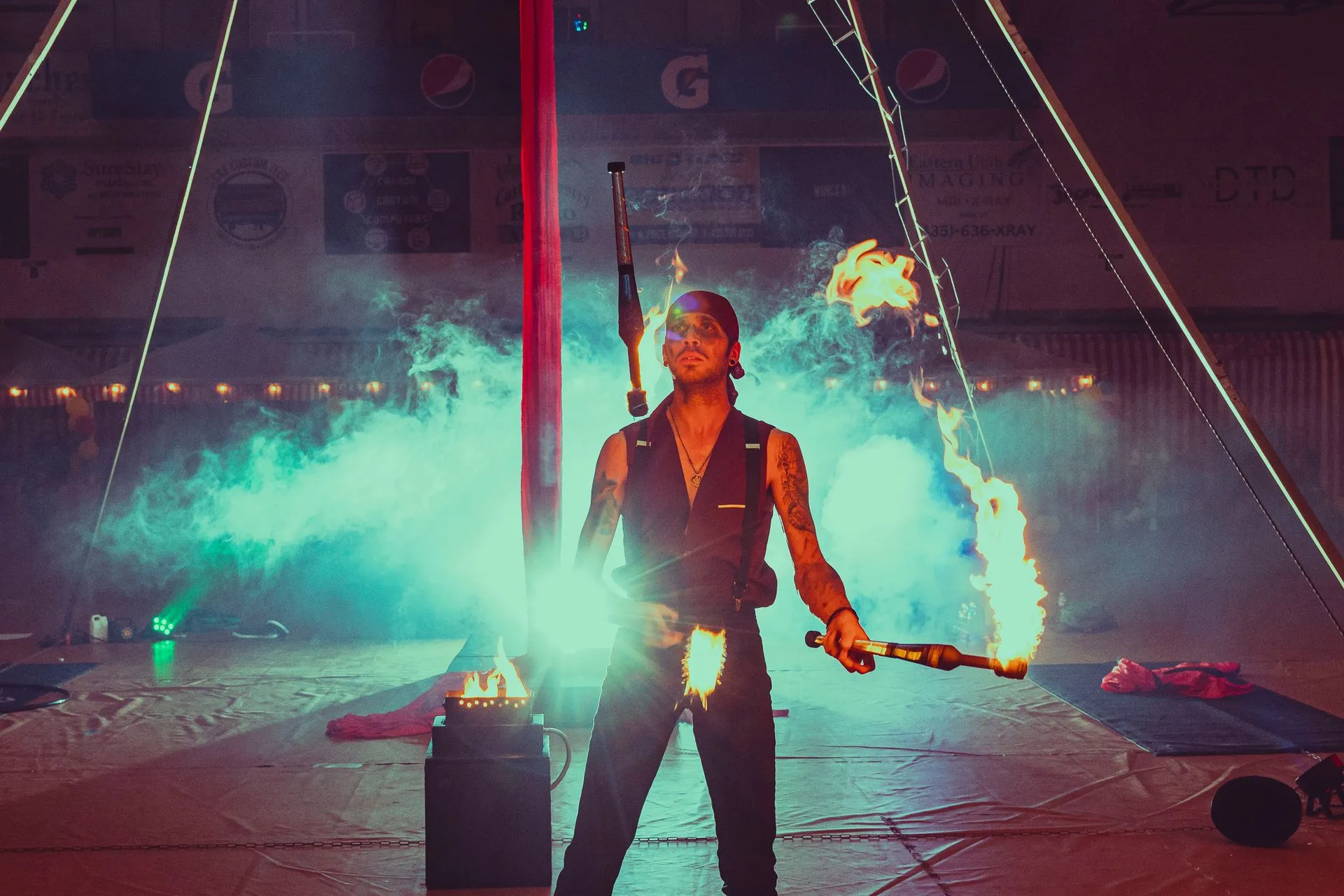 A man is holding a fire stick in a circus tent.