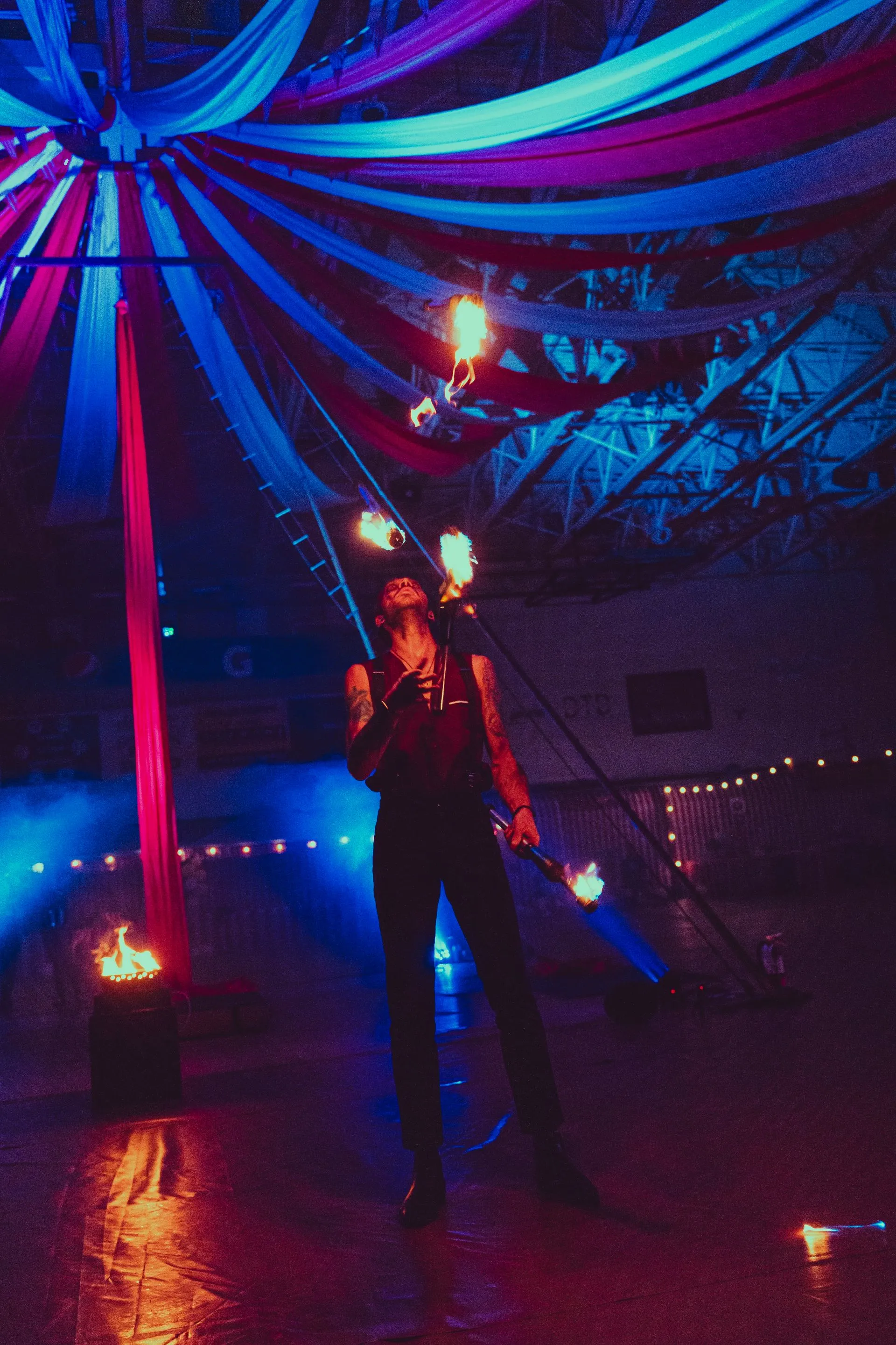 A man is juggling fire in a dark room.