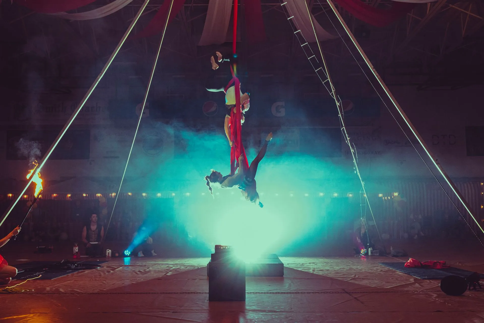 A group of people are performing aerial acrobatics in a circus tent.