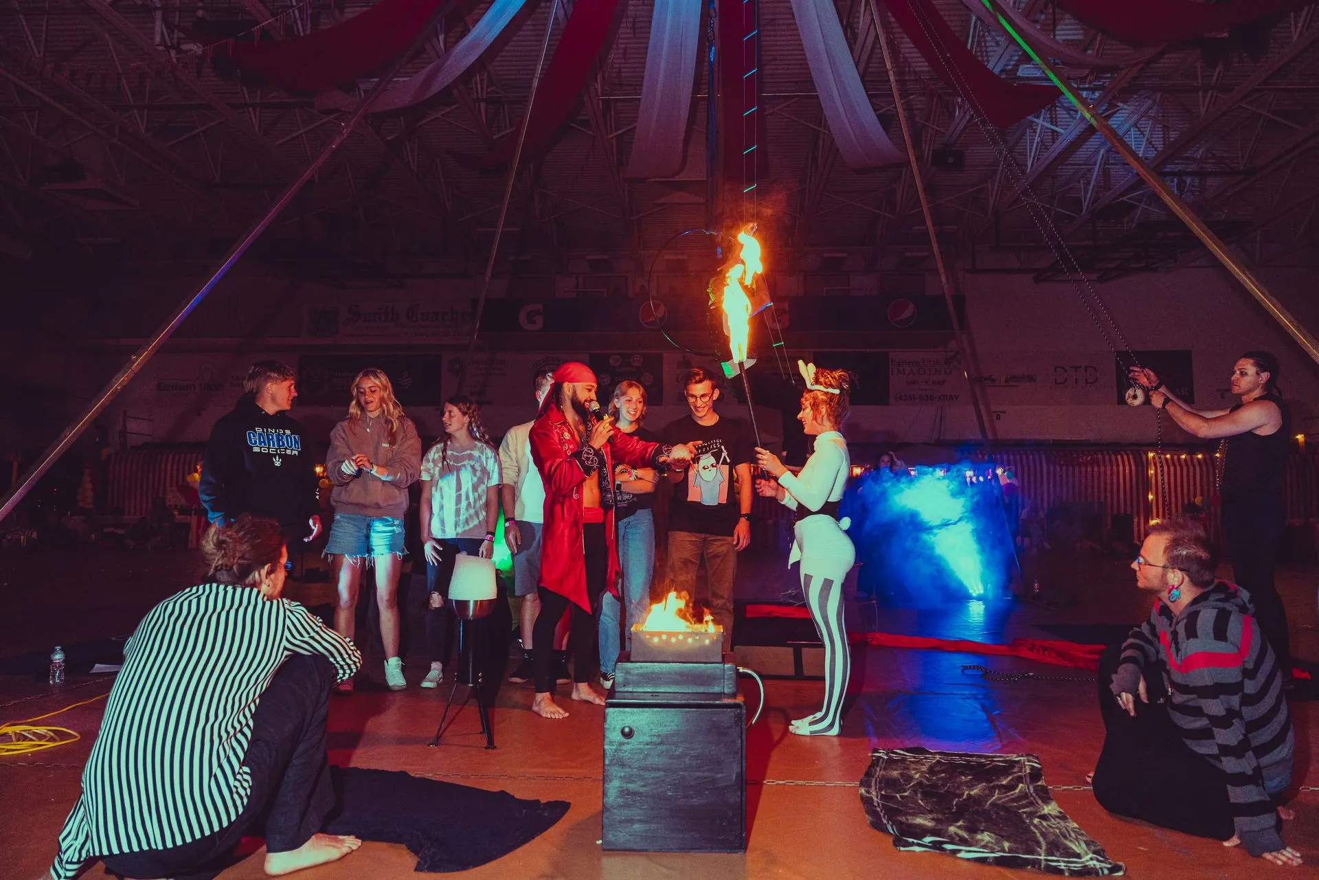 A group of people are standing around a fire in a tent.