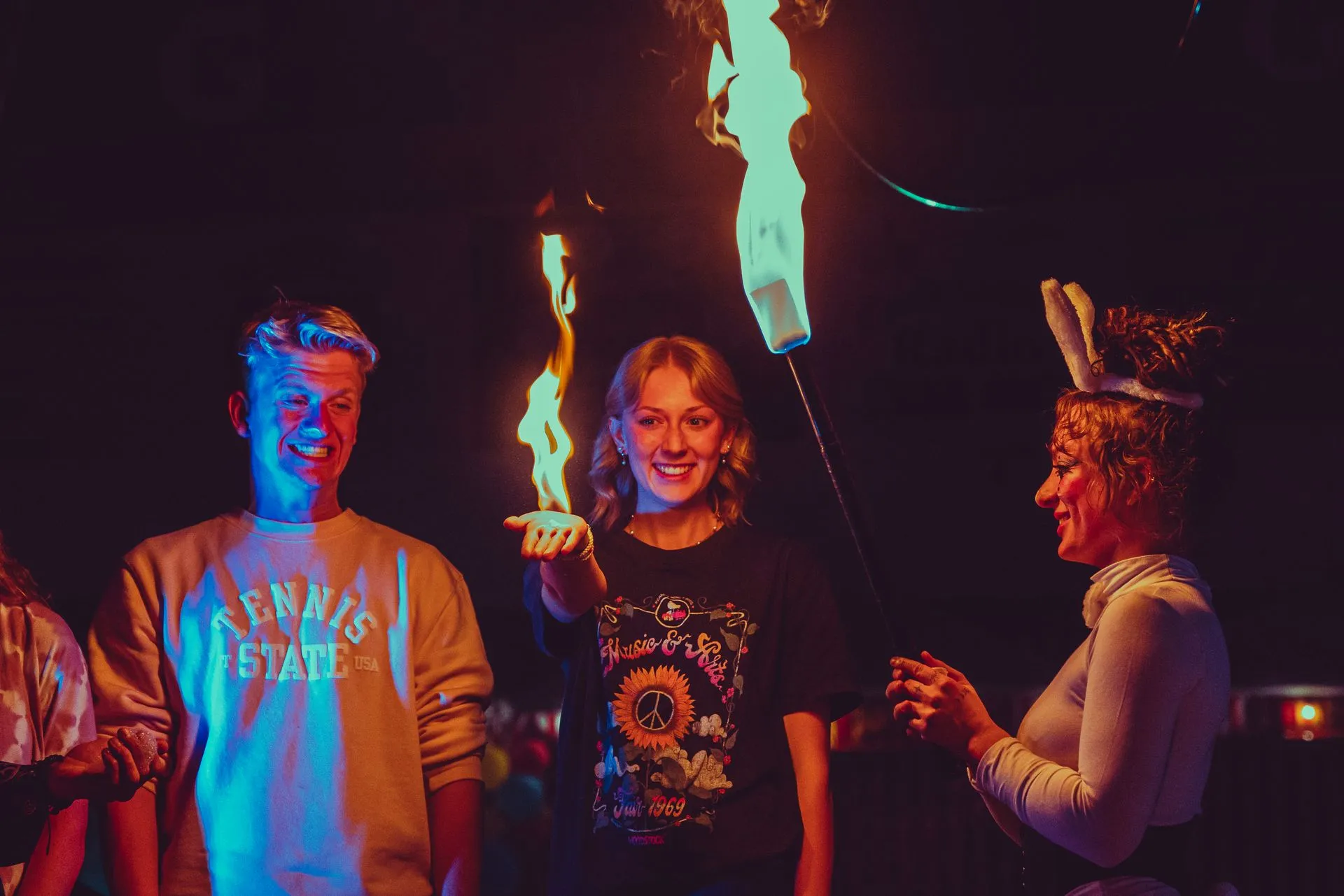 A group of people are standing in a dark room holding a fire torch.