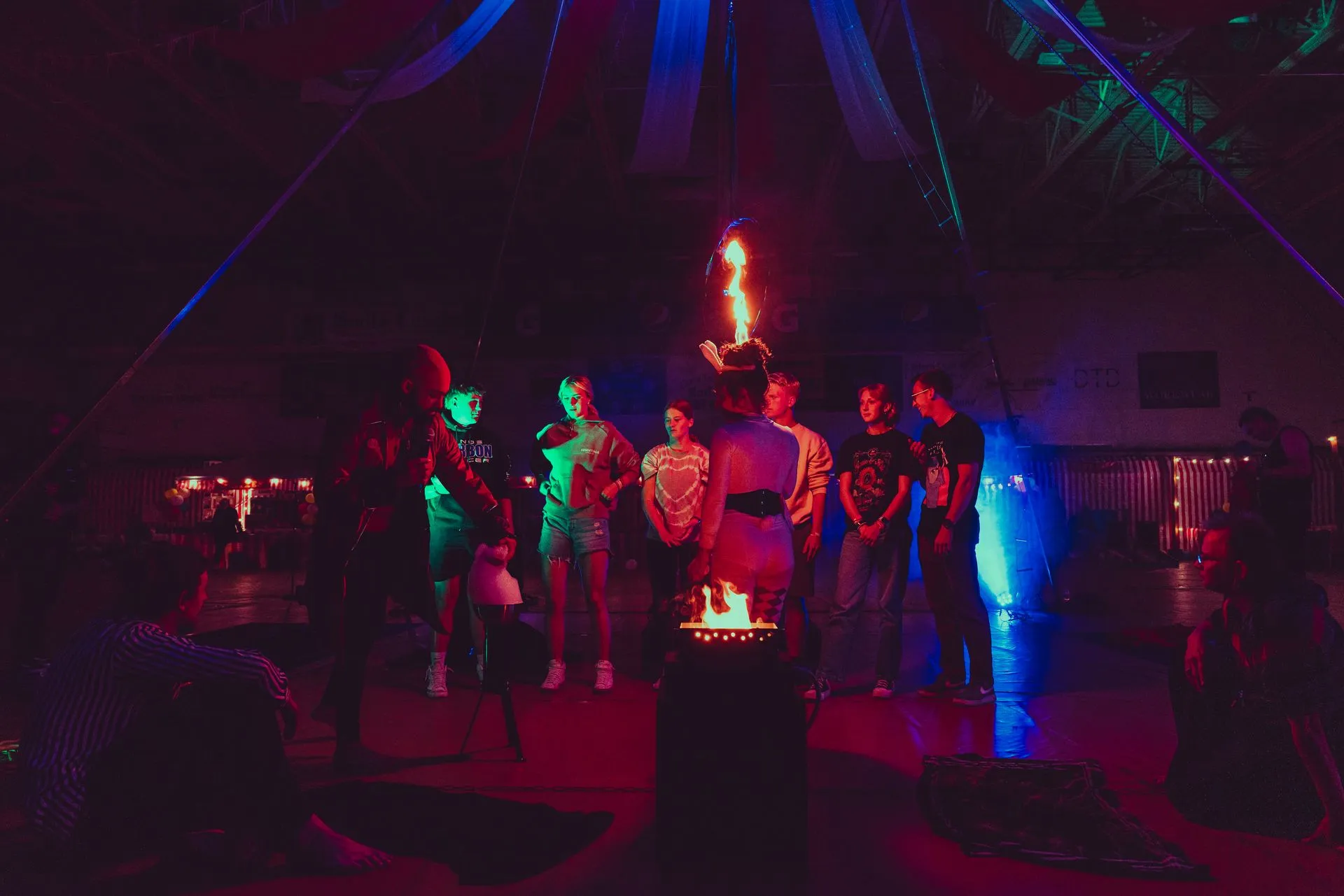 A group of people are standing around a fire in a dark room.