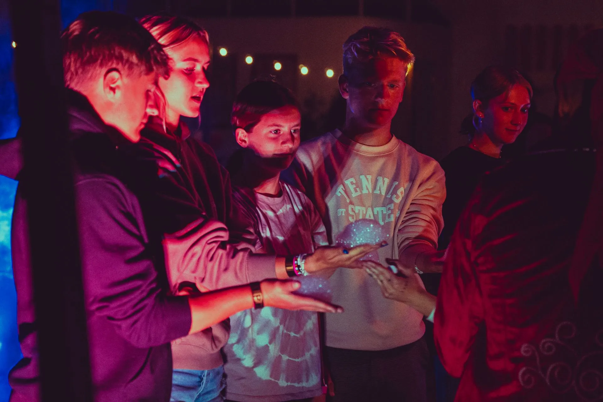 A group of people are standing in a circle in a dark room.